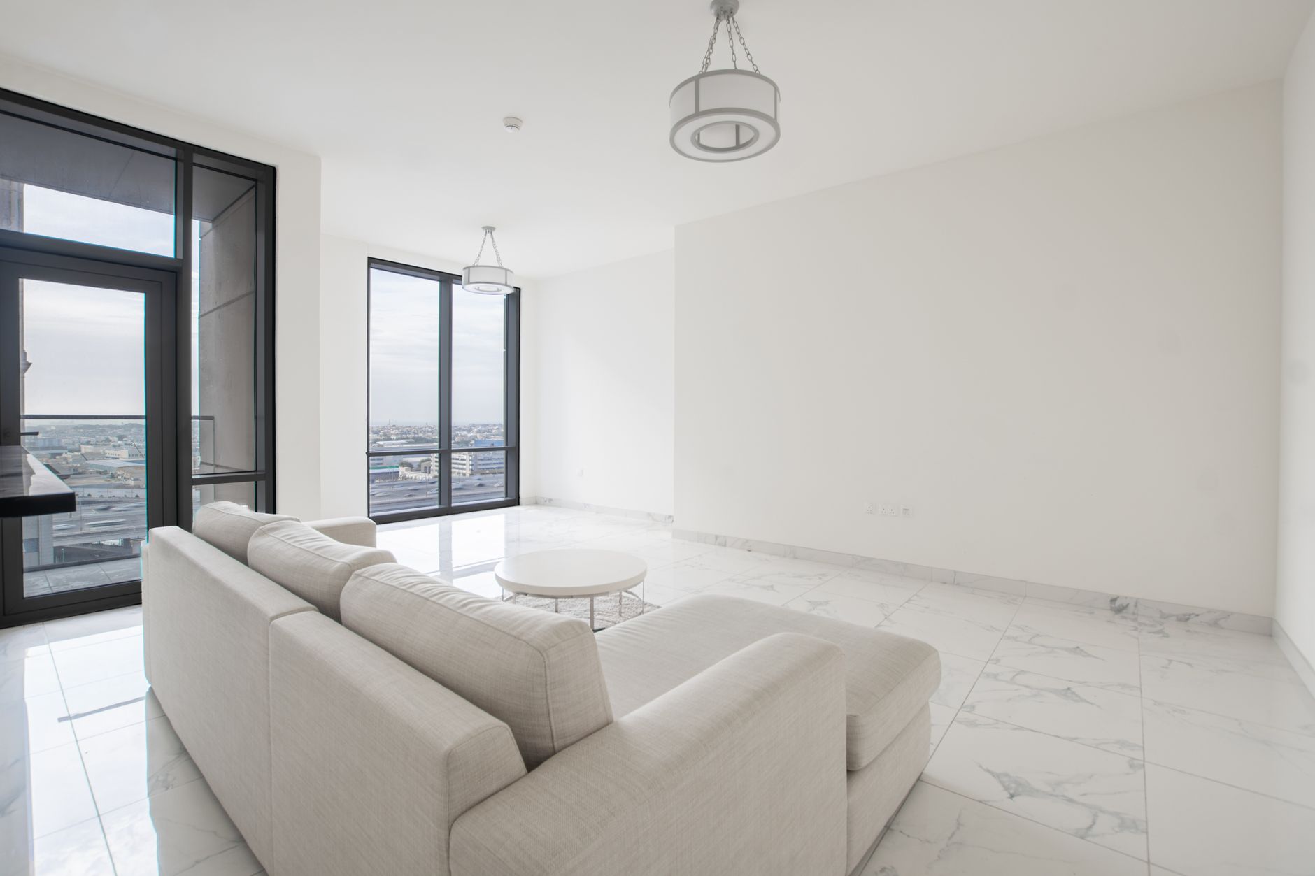 Spacious and bright minimalist living room with a city view, featuring large windows and a contemporary design. — Trójmiasto