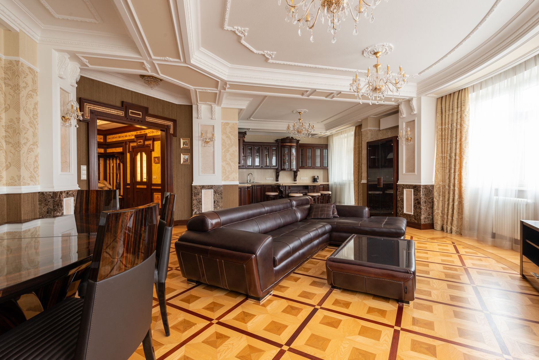 Spacious living room with elegant interior design featuring a leather sofa and chandeliers. — Trójmiasto