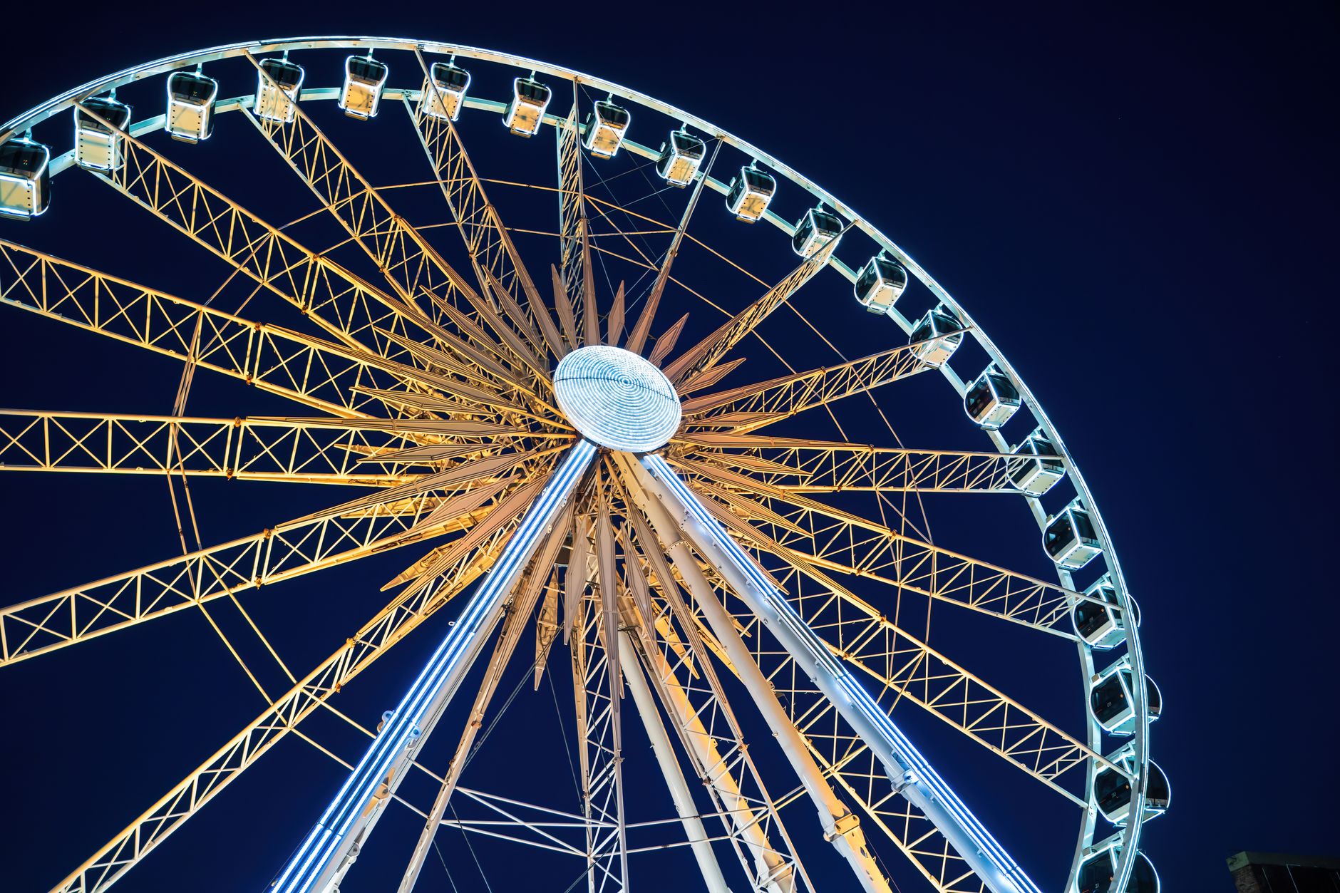 Low angle night shot of a brightly lit Ferris wheel in Gdańsk, Poland. — Trójmiasto