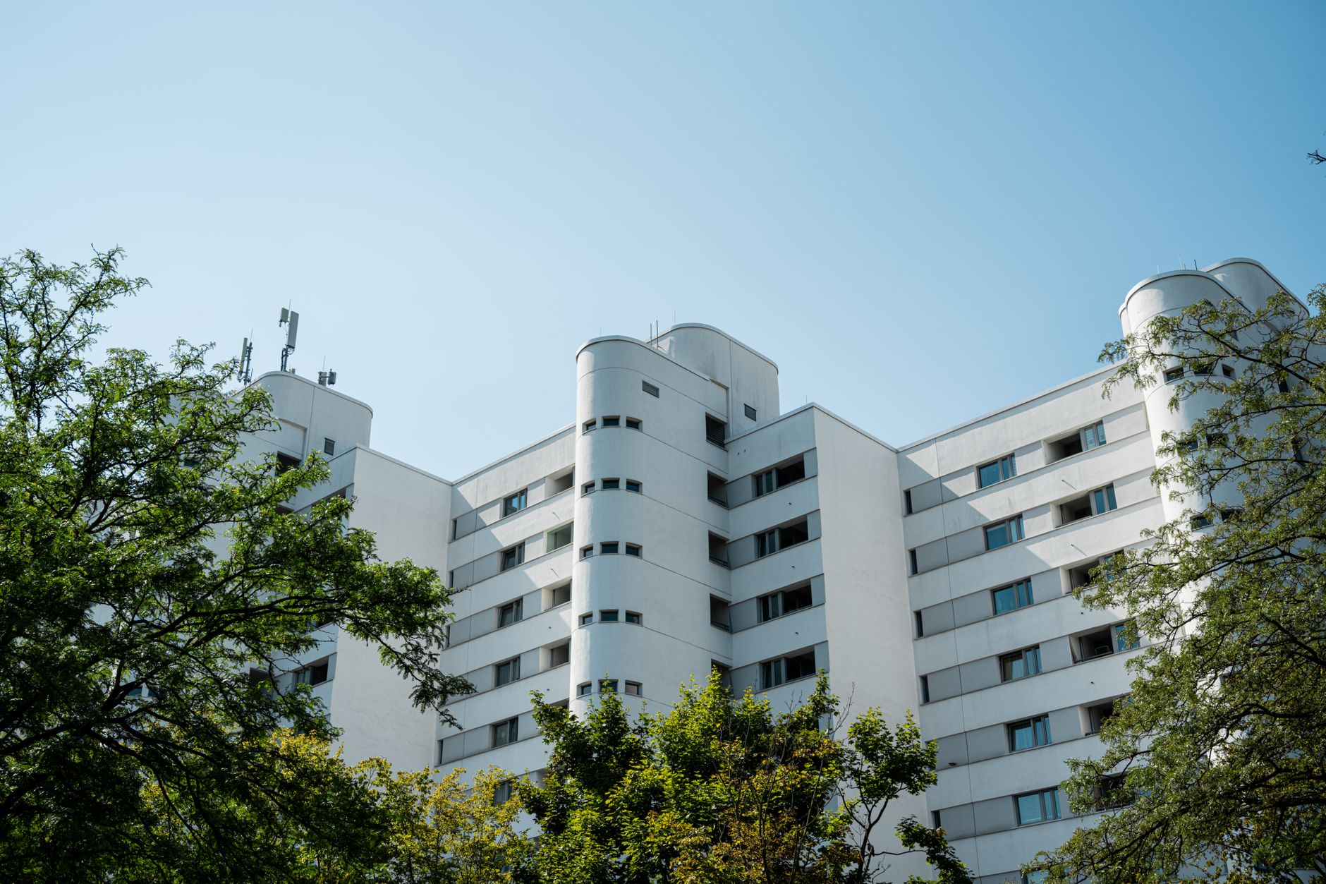 A contemporary high-rise building with a clear blue sky and trees in an urban setting. — Trójmiasto