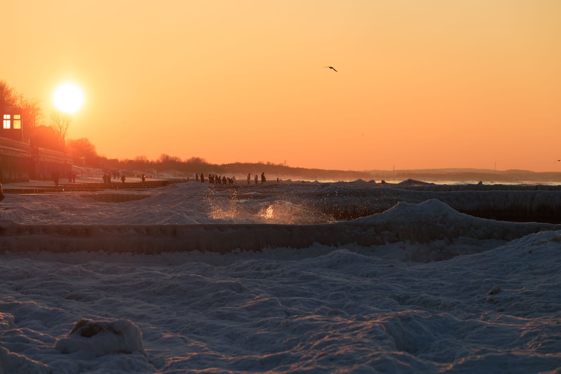 Explore the stunning winter sunrise along the icy shores of Zelenogradsk, Russia, featuring silhouettes against a golden sky. — Trójmiasto