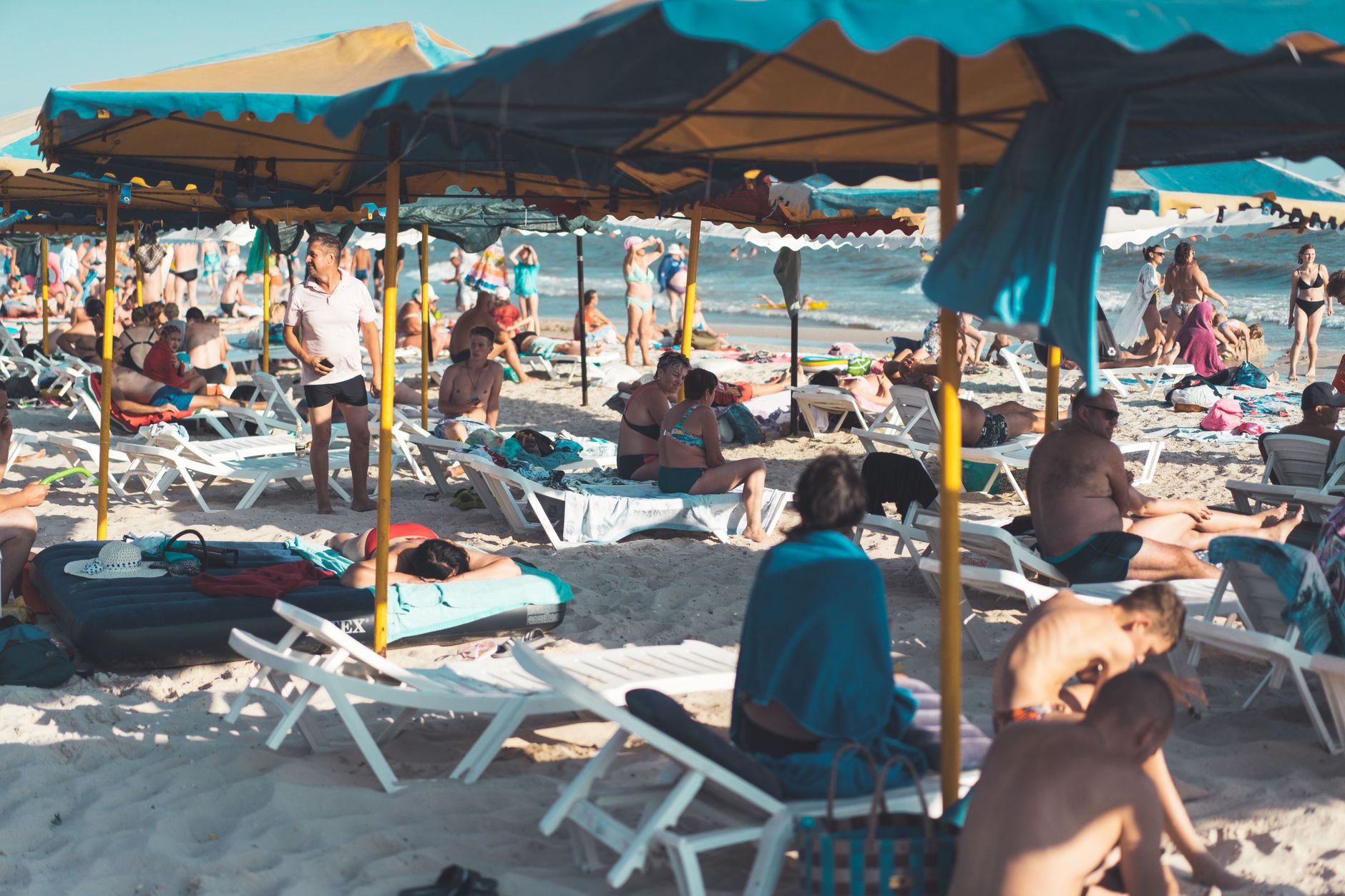Lively summer beach with sunbathers, umbrellas, and chairs, showcasing a vibrant vacation atmosphere. — Trójmiasto