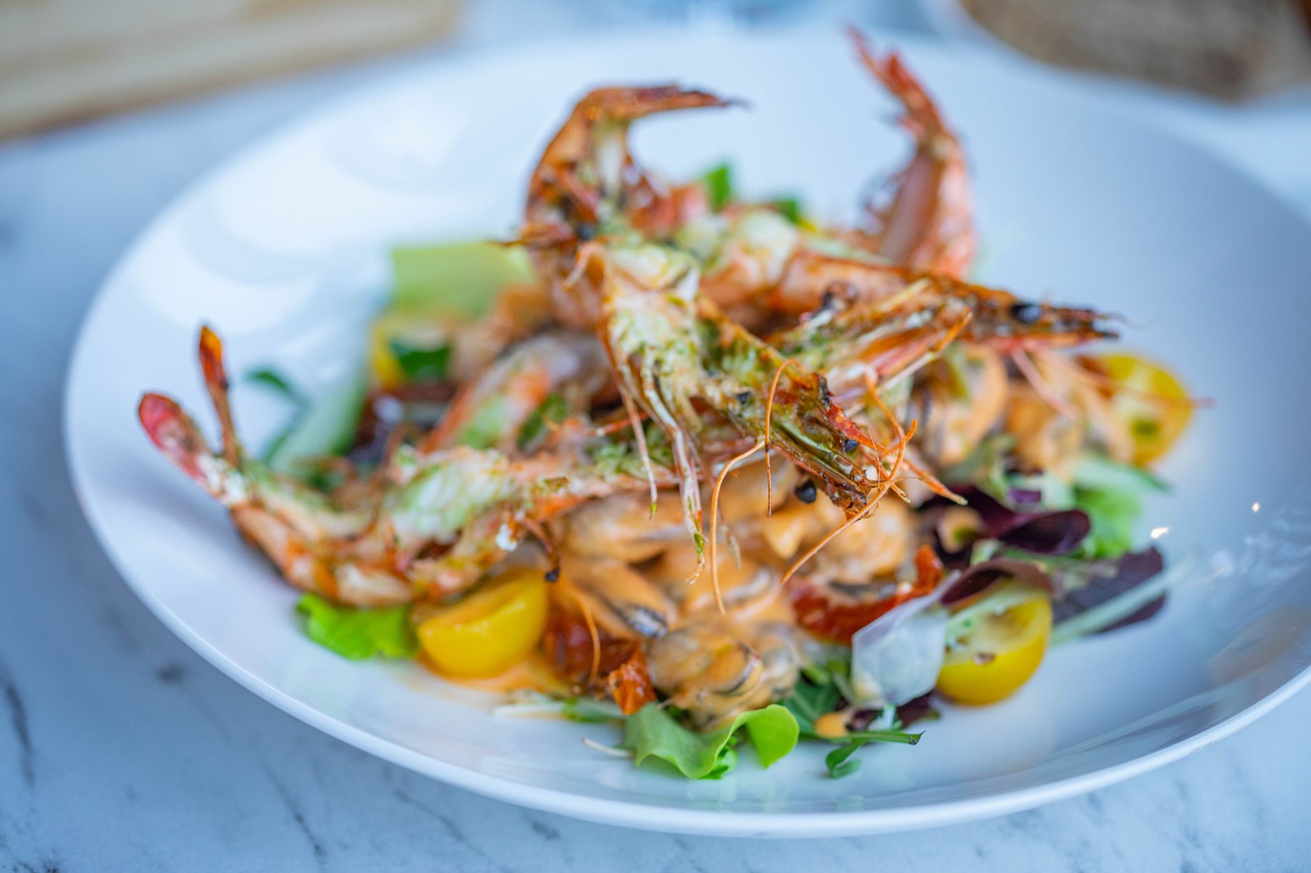 Close-up of a gourmet prawn salad with fresh vegetables on a white plate. — Trójmiasto