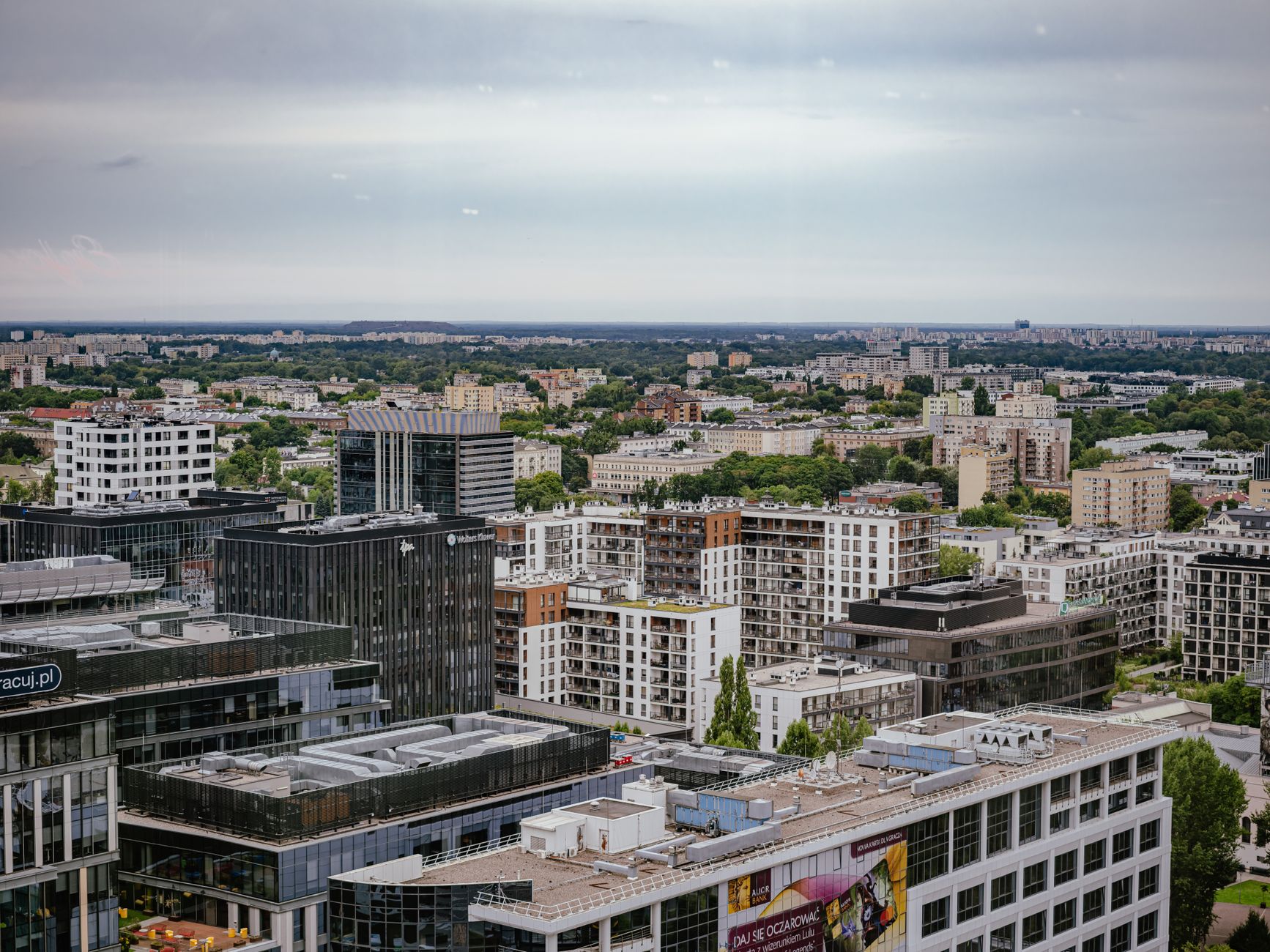 Aerial view of Warsaw showcasing modern and residential architecture against a lush backdrop. — Trójmiasto