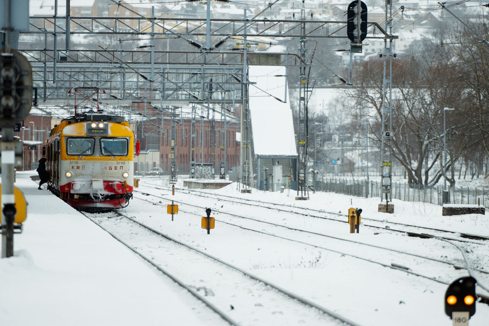 A yellow train arriving at Jönköping station, Sweden, surrounded by winter snow. — Trójmiasto