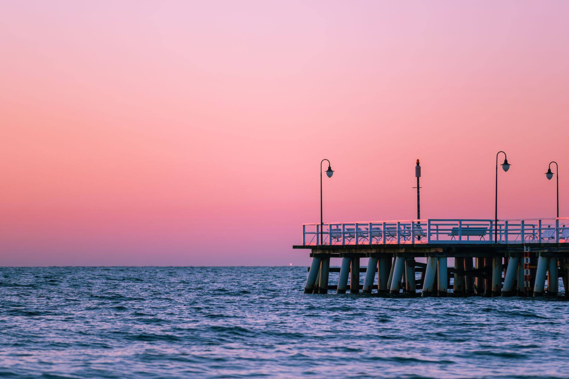 Serene pier over the sea during sunset with a vibrant pink sky in Gdynia, Poland. — Trójmiasto
