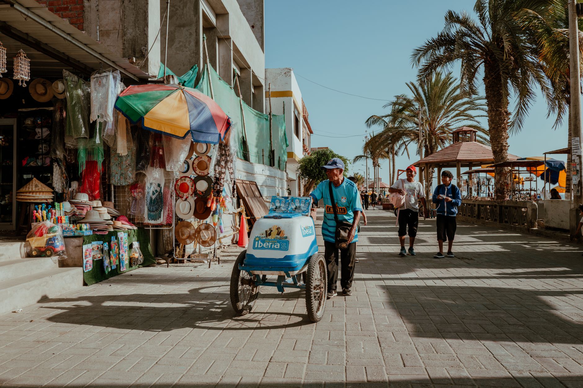 Street vendor selling beverages in Pacasmayo, Peru, near colorful market stalls on a sunny day. — Trójmiasto