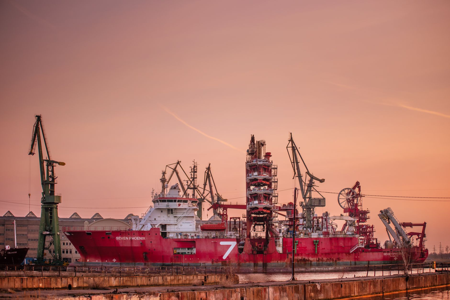 Industrial ship moored in Gdańsk harbor at sunset with cranes in view. — Trójmiasto