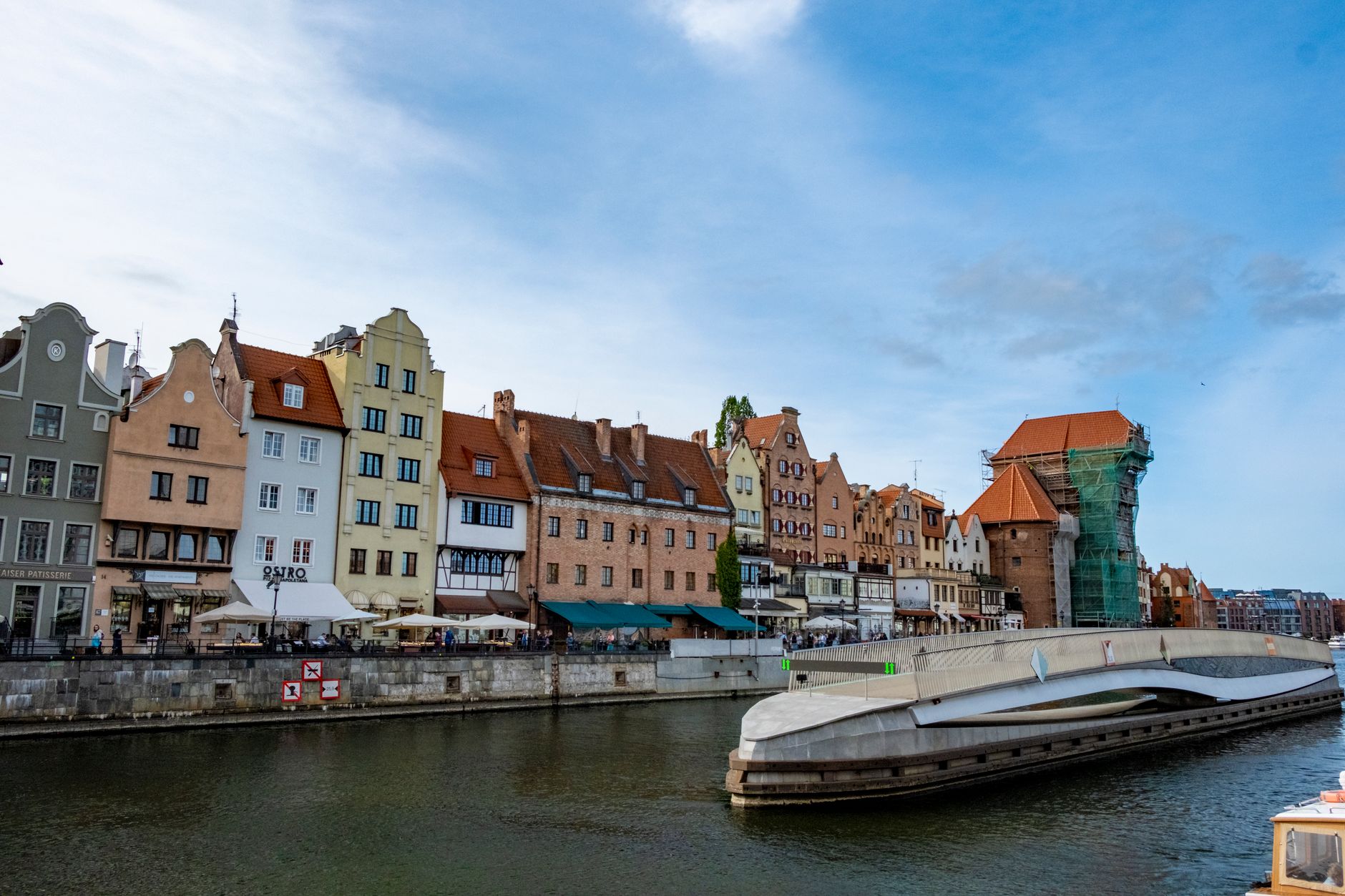 Charming riverside architecture in Gdańsk, showcasing historical buildings and a modern bridge. — Trójmiasto