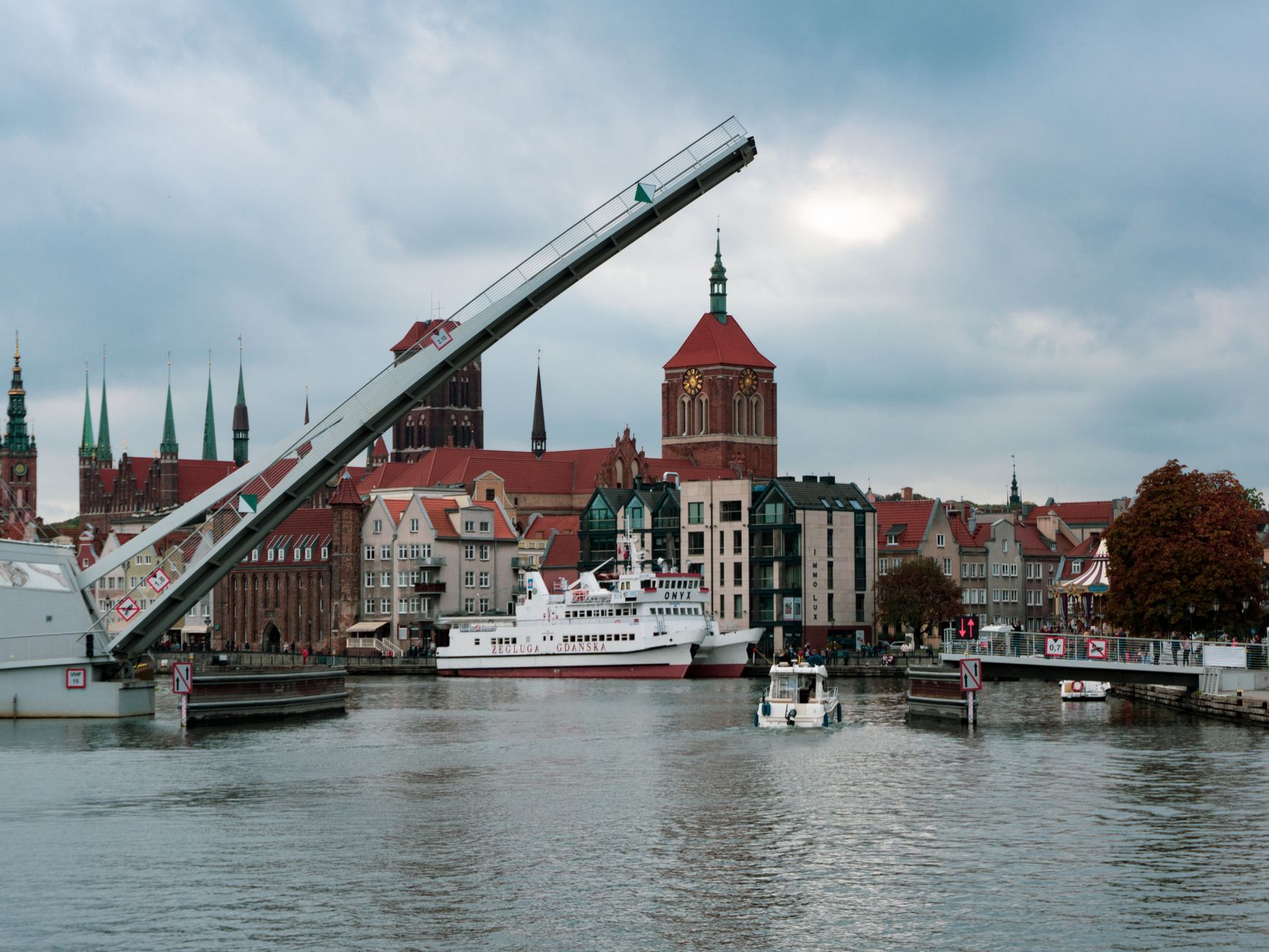 Picturesque view of Gdańsk with a lifted drawbridge over the river, featuring a ferry and historic architecture. — Trójmiasto