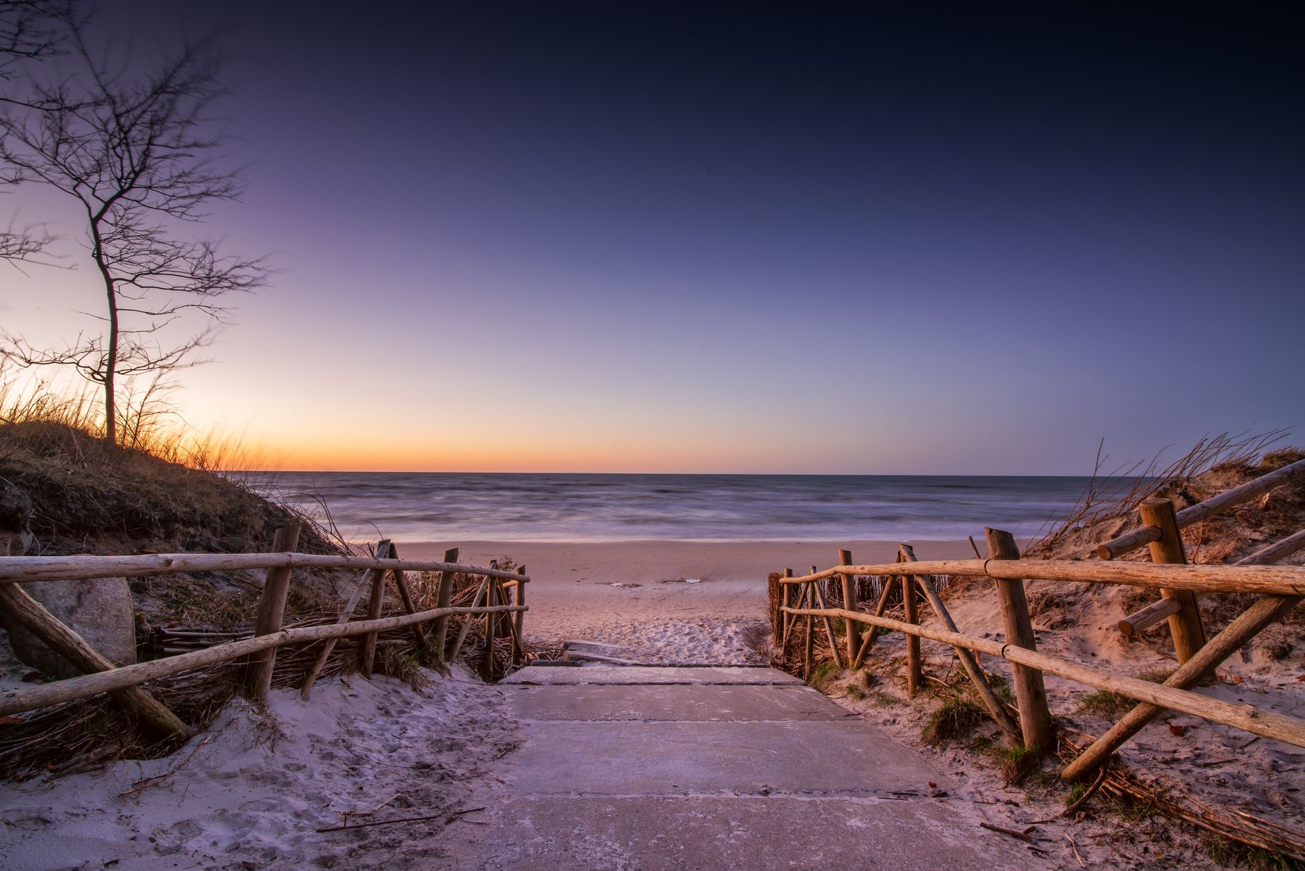 Picturesque seascape of empty pathway leading to calm water with sandy beach under cloudless sky — Trójmiasto