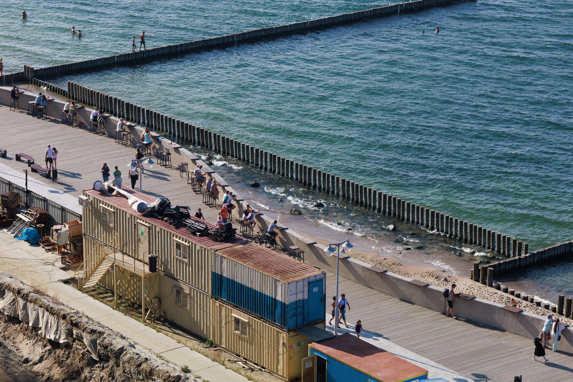 A busy coastal boardwalk with people enjoying a sunny day by the sea. — Trójmiasto