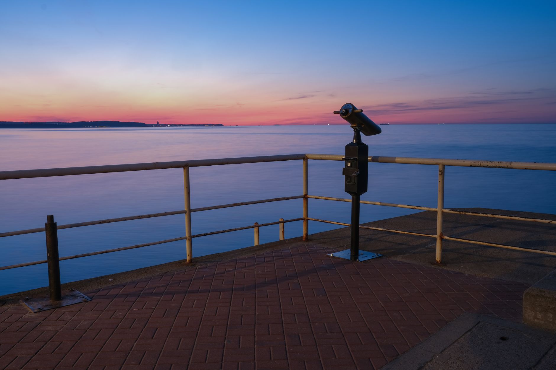 Serene twilight scene of a seaside promenade in Gdańsk, featuring calm waters and a viewing telescope. — Trójmiasto