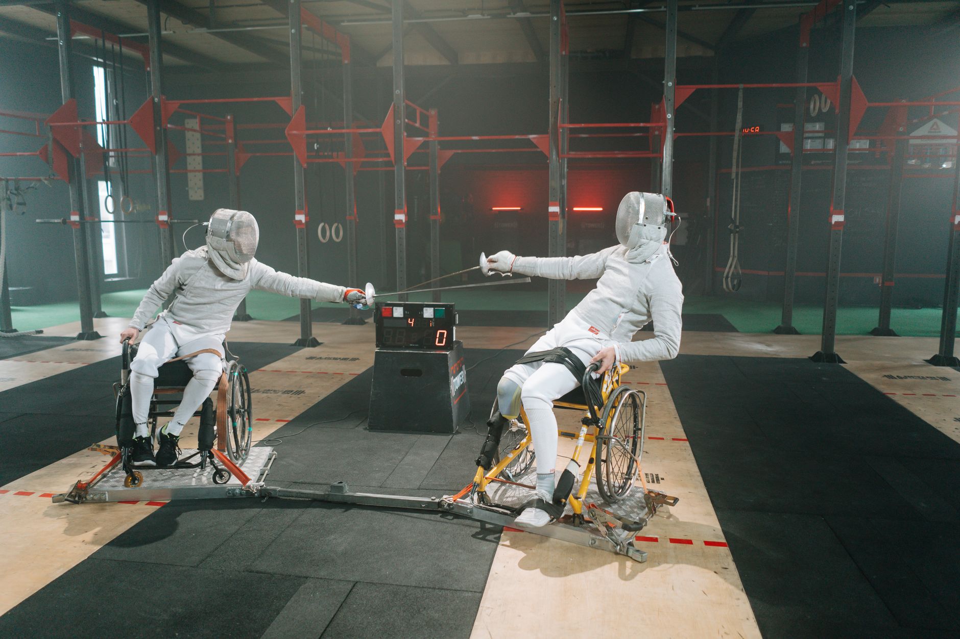 Two wheelchair fencers engaging in a competitive indoor fencing match. — Trójmiasto