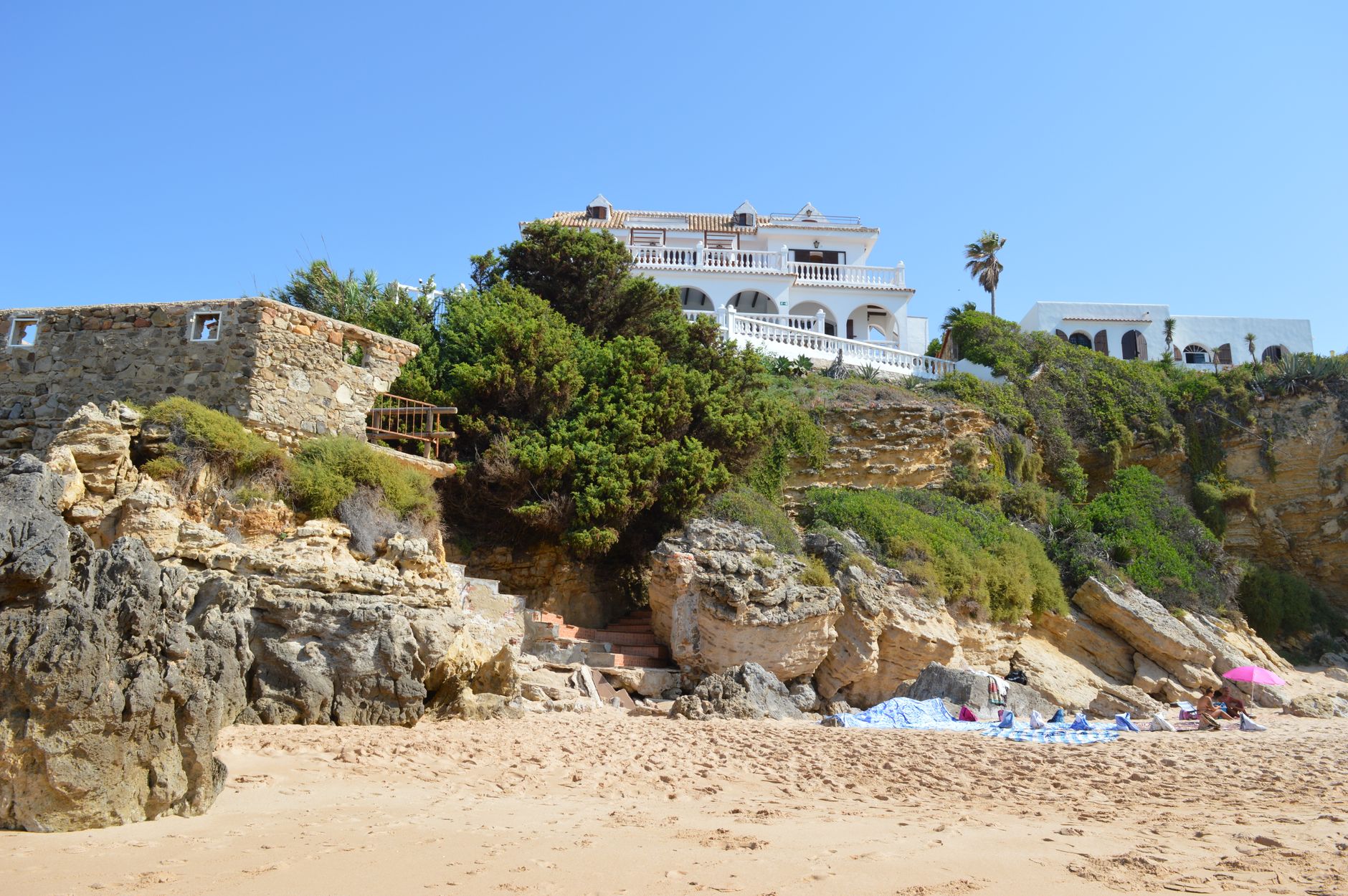 Picturesque seaside villa atop rocky cliffs with vibrant greenery under a clear blue sky. — Trójmiasto