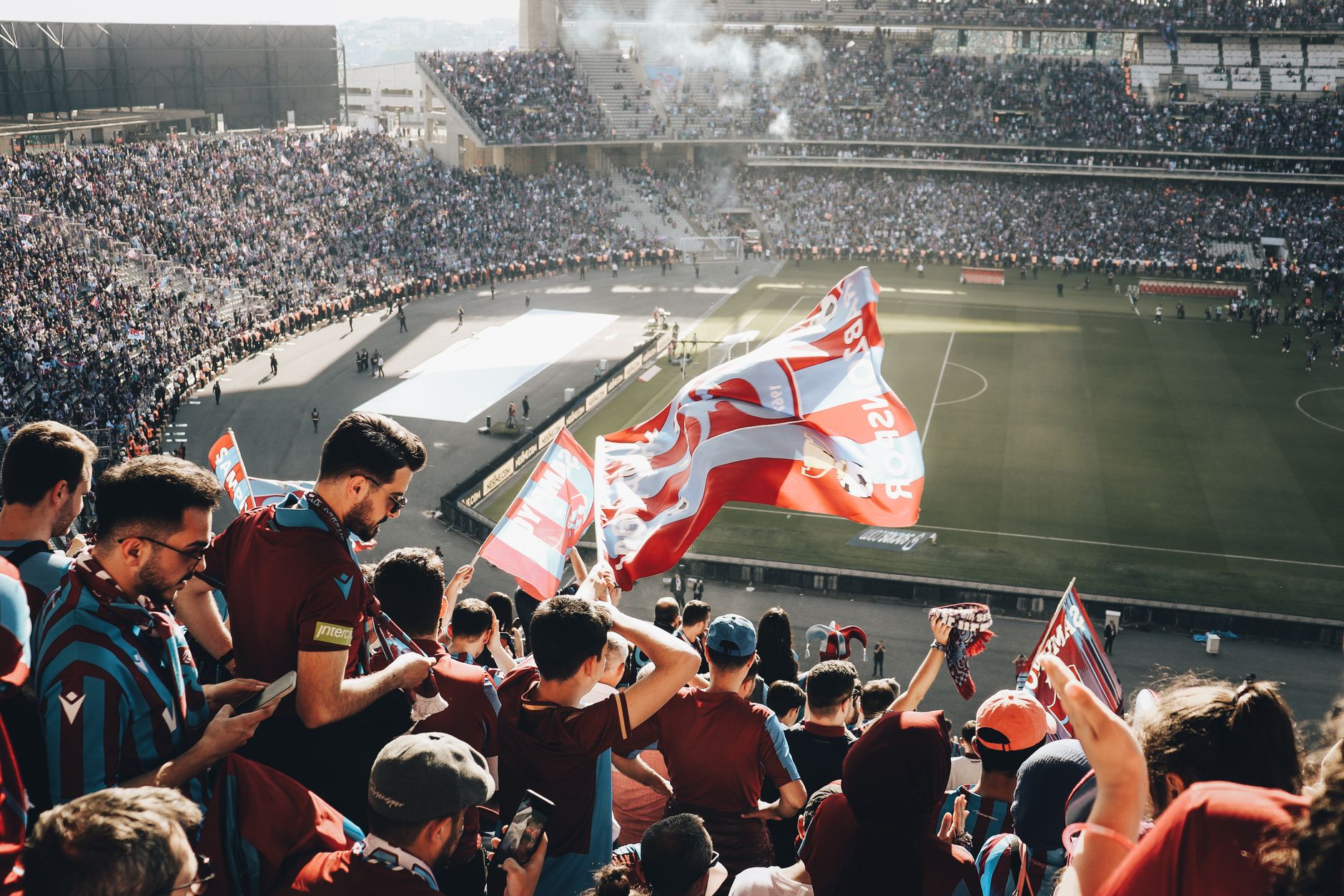 Vibrant crowd with flags cheering at a football stadium during the day. — Trójmiasto