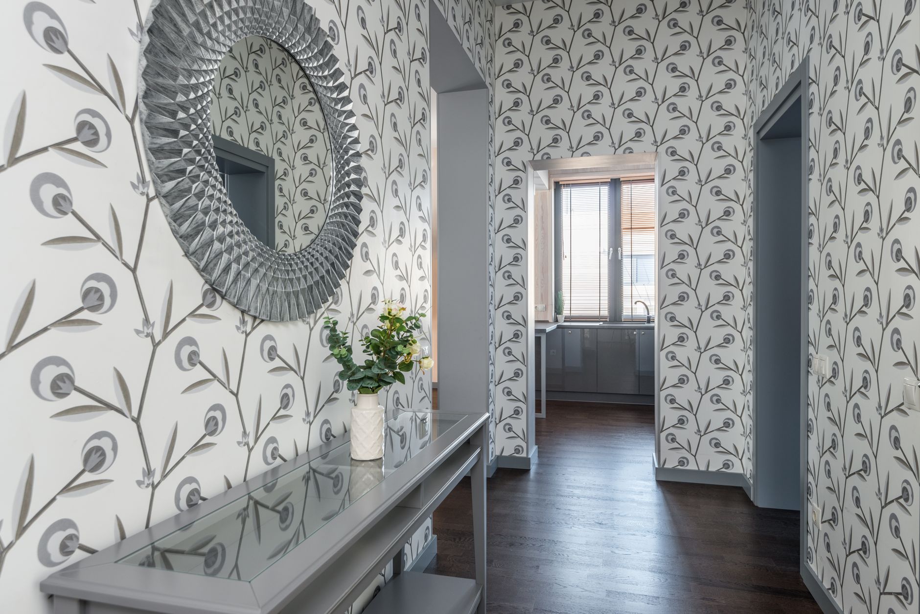 Contemporary hallway featuring decorative wallpaper, a mirror, and a table with flowers, creating an elegant atmosphere. — Trójmiasto