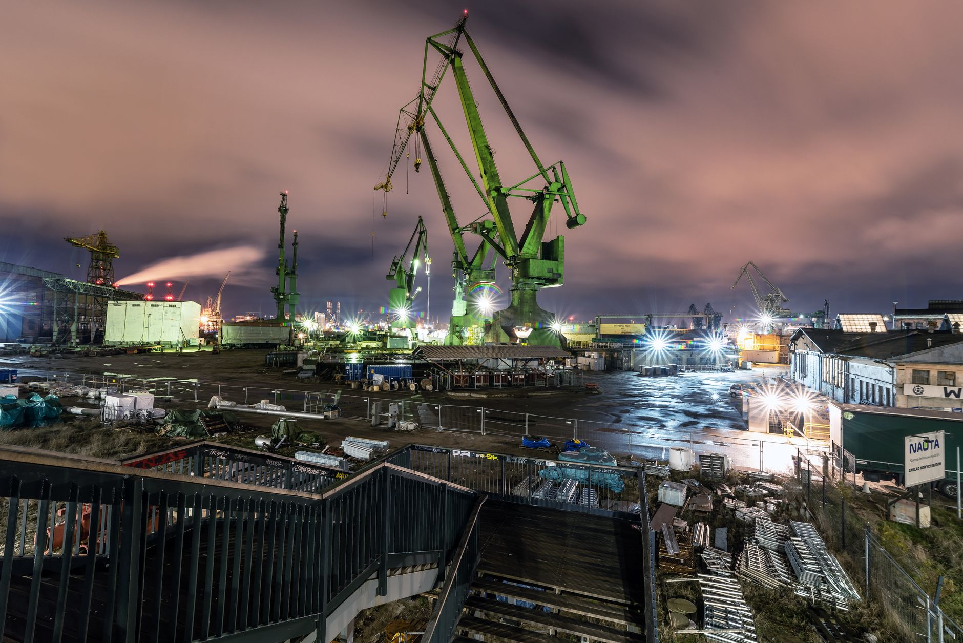 Modern metal cranes and cargo ships in industrial port under cloudy evening sky in city — Trójmiasto