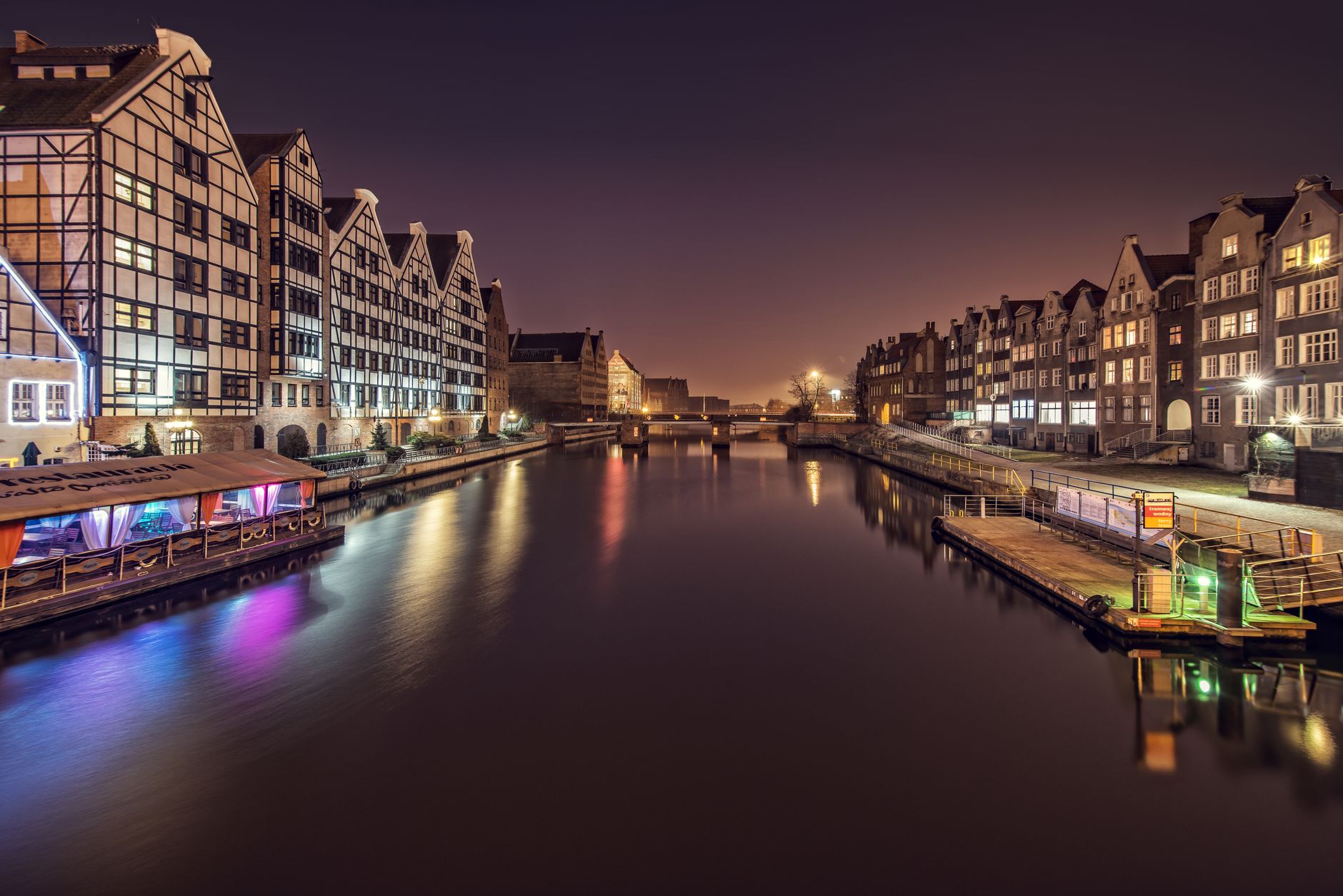 Water channel between multistage building exteriors and shiny lights at dusk in Amsterdam Netherlands — Trójmiasto