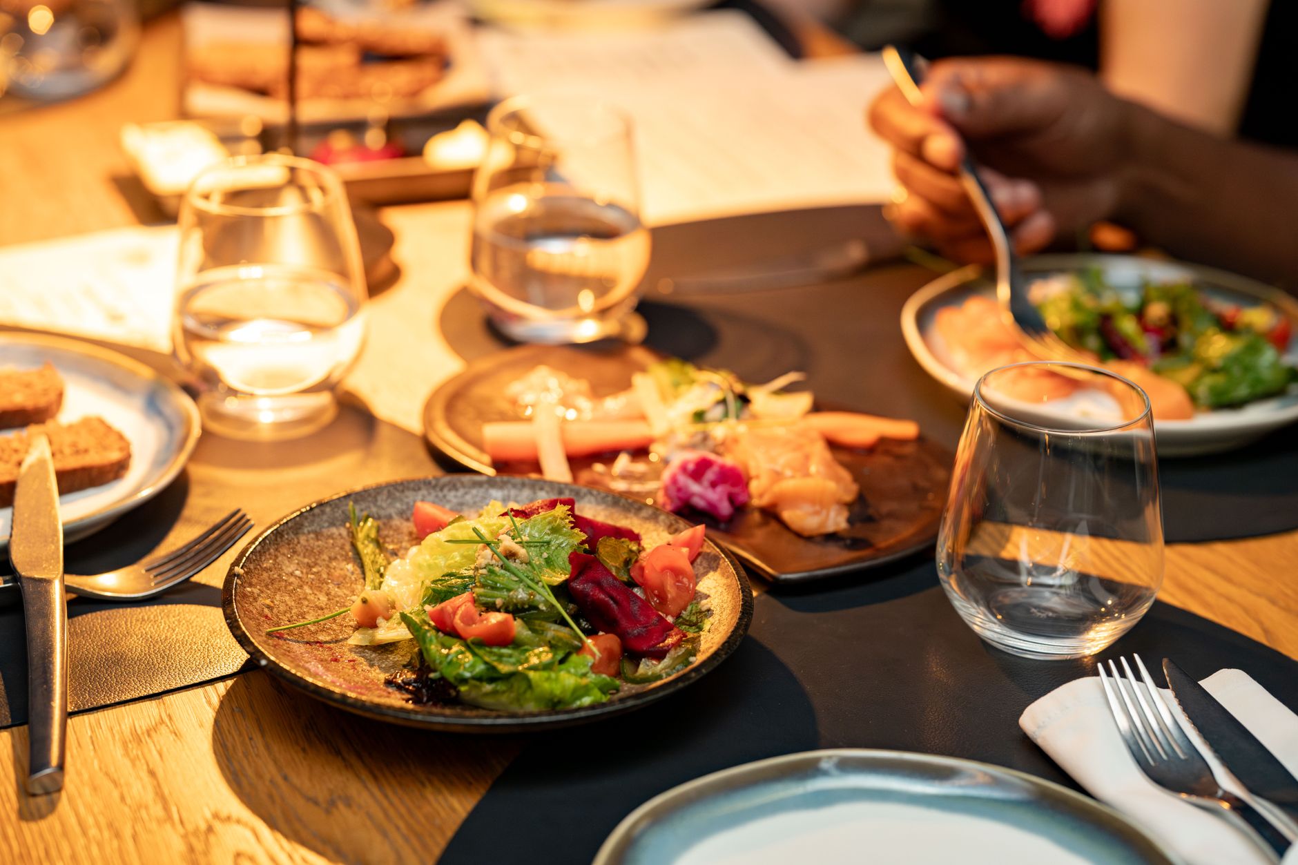 A beautifully set dinner table with gourmet salads and glassware, ideal for a classy dining experience. — Trójmiasto