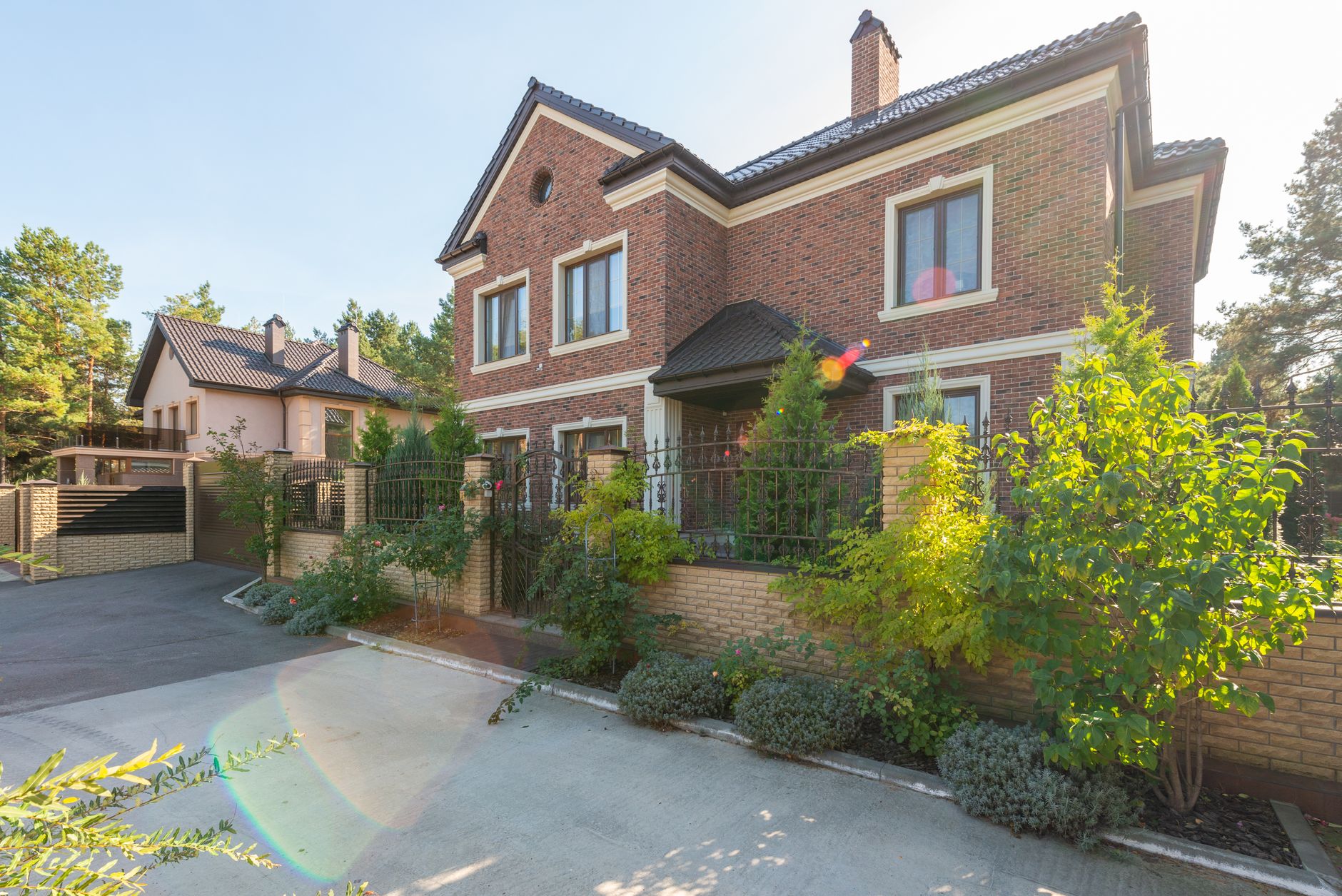 Elegant brick house with a lush garden and driveway, under a clear sky. — Trójmiasto