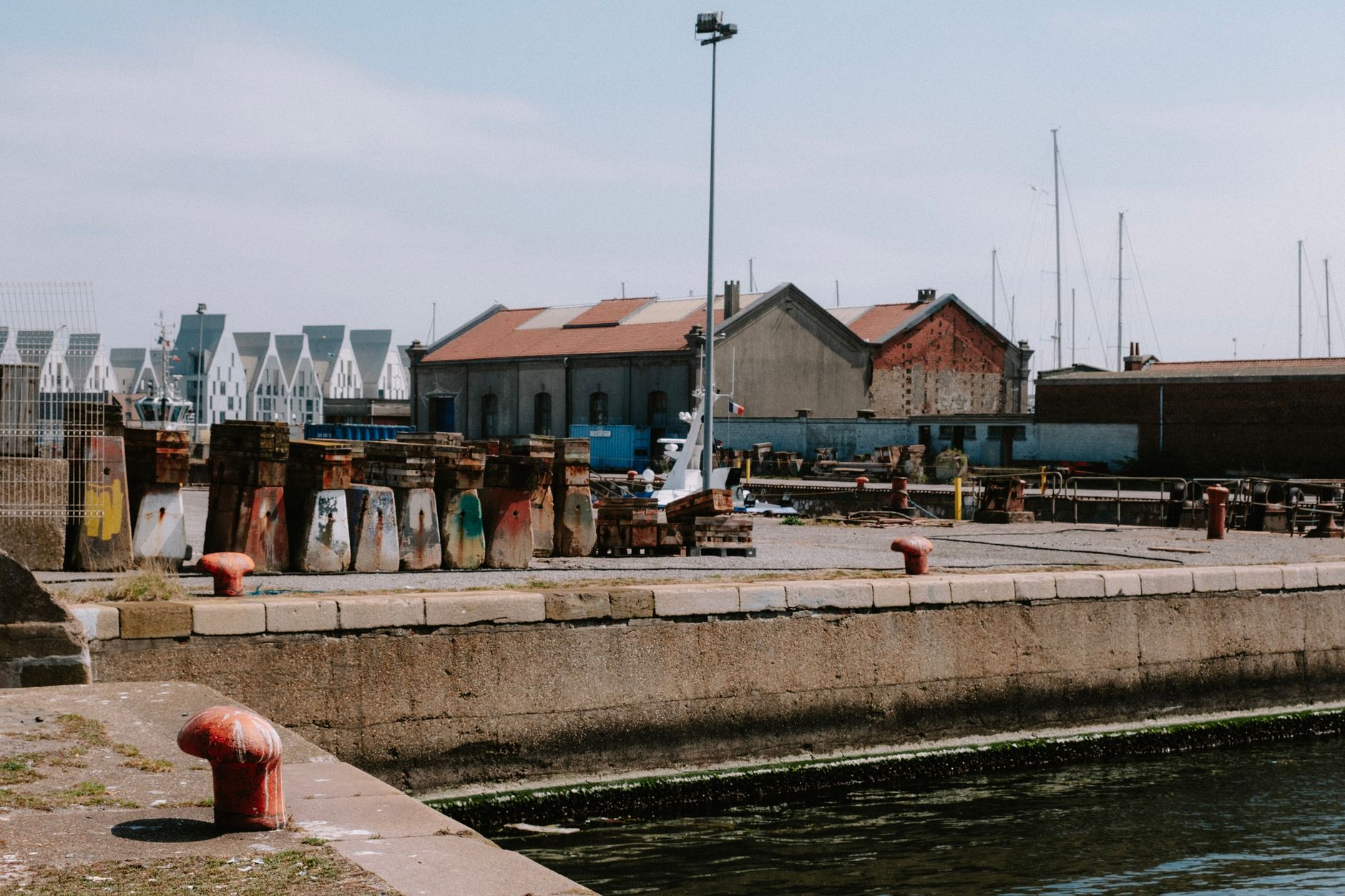 Explore an industrial harbor scene with aged buildings and colorful quay structures under a clear sky. — Trójmiasto