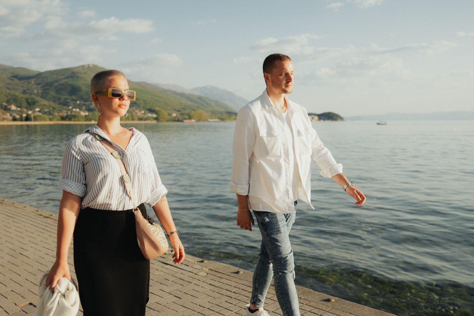 A fashionable couple walking on a promenade beside the sea, enjoying a sunny day. — Trójmiasto