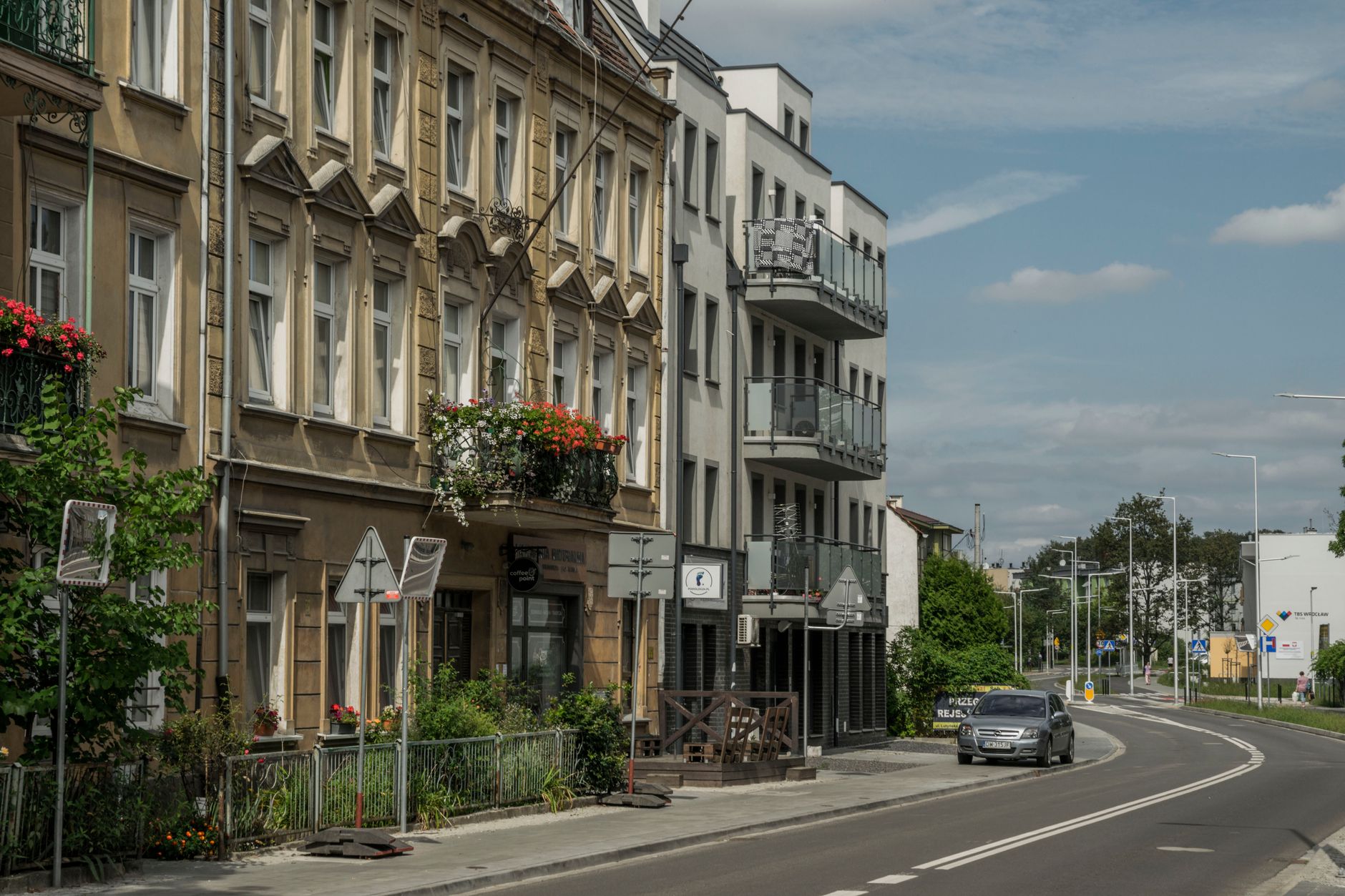 Street view of residential buildings and a car in Wrocław, showcasing city life. — Trójmiasto