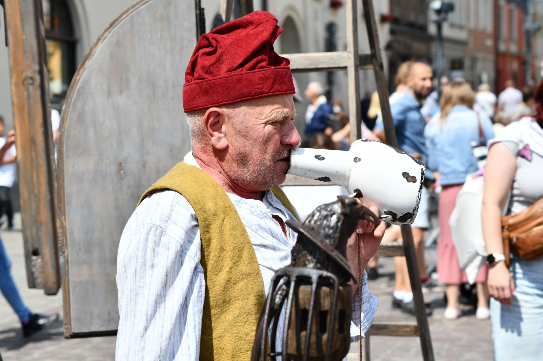 A street performer dressed in traditional clothing captivates an audience with his act on a bustling city street. — Trójmiasto