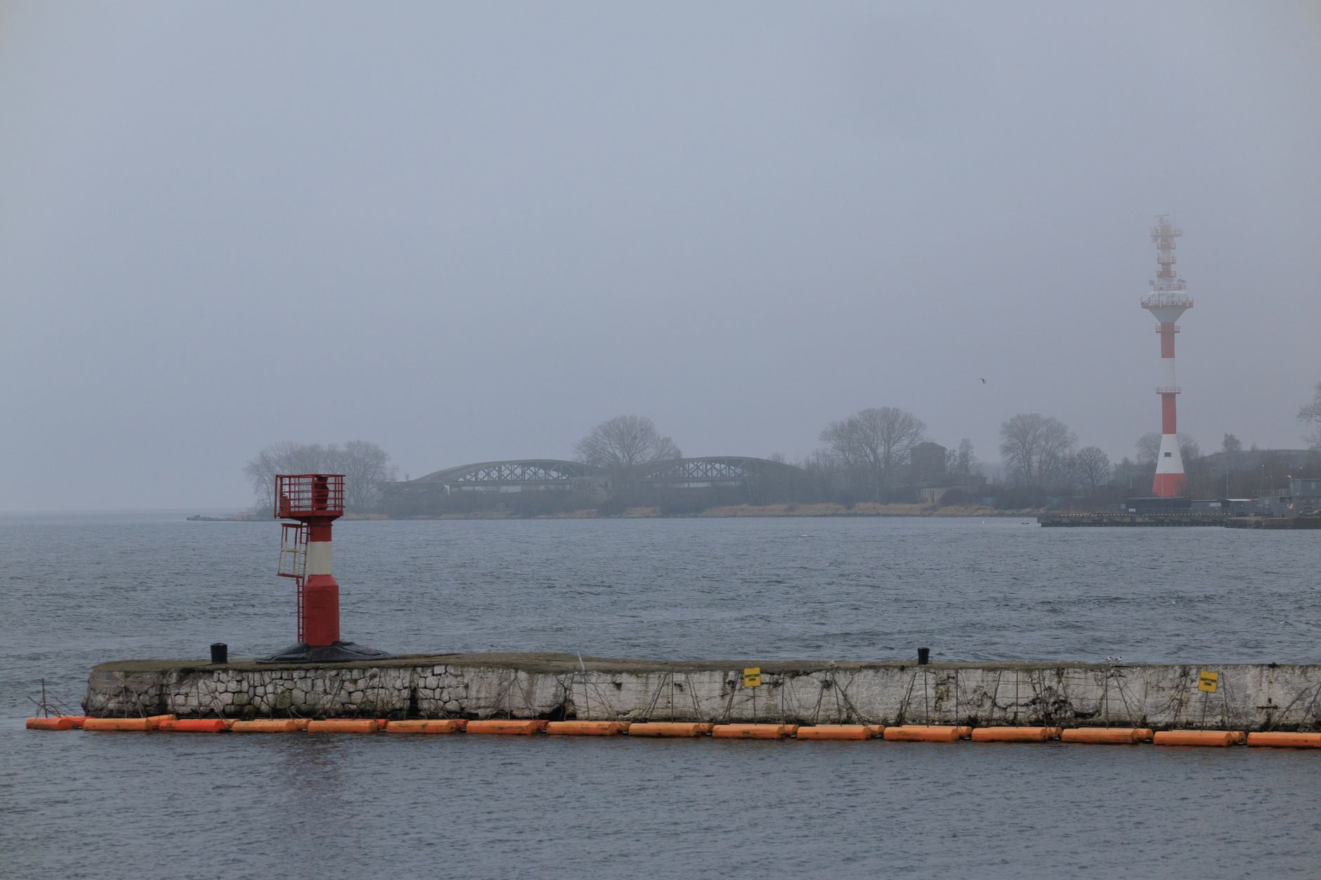 Overcast day at Baltiysk waterfront showing buoys, beacon, and lighthouse. — Trójmiasto