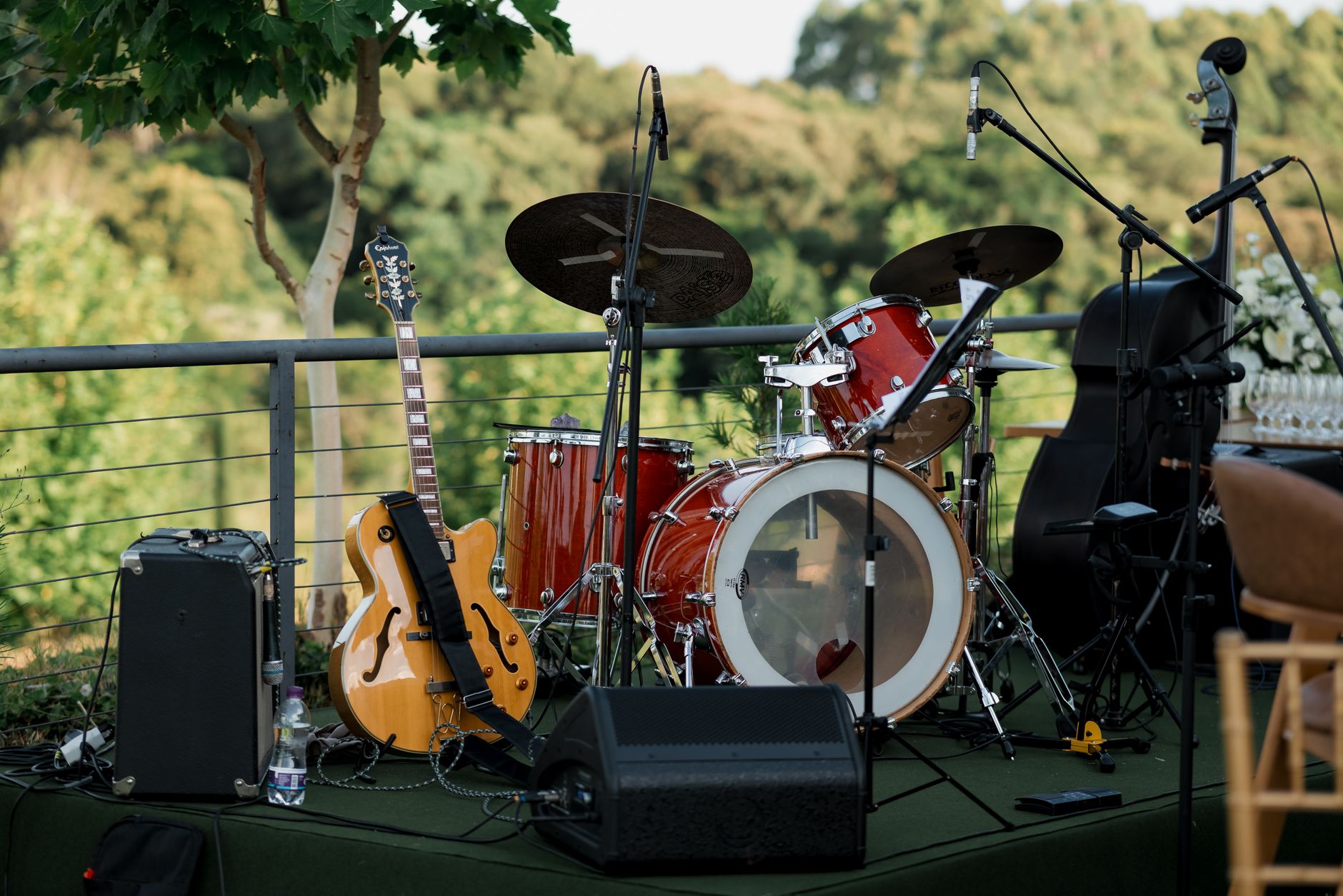 An outdoor stage setup with a drum set, guitar, and amplifier amidst greenery. — Trójmiasto