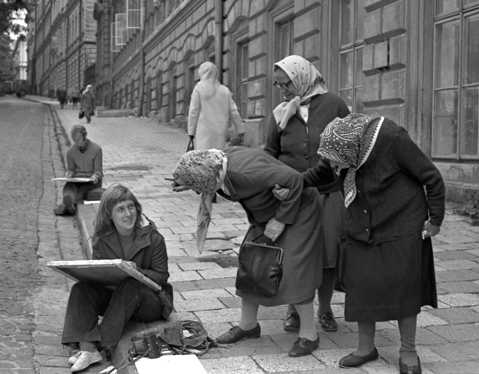 Elderly women interact with a street artist in a vintage cobblestone alley. — Trójmiasto