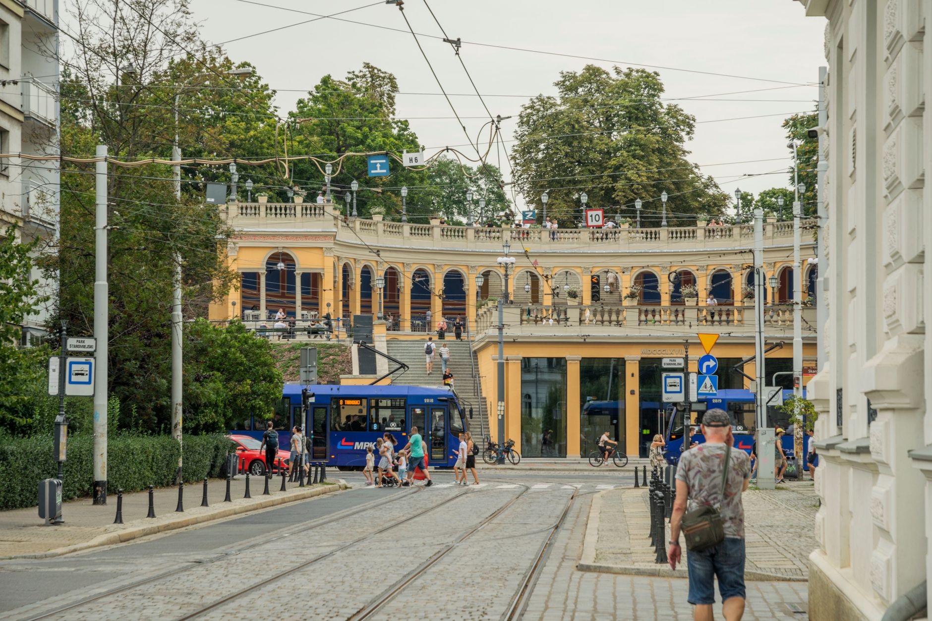 A vibrant street scene in Wrocław showing trams, people, and historic architecture. — Trójmiasto