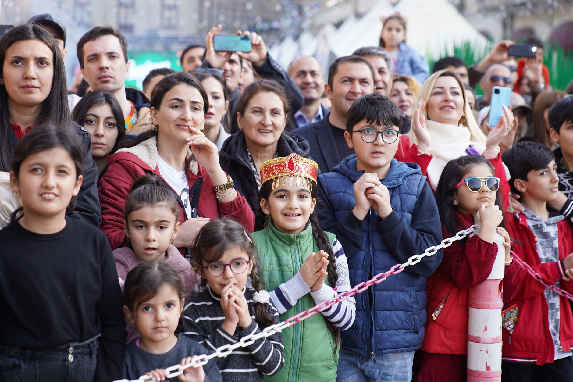 A diverse group of adults and children enjoy an outdoor festival, capturing joyful expressions. — Trójmiasto