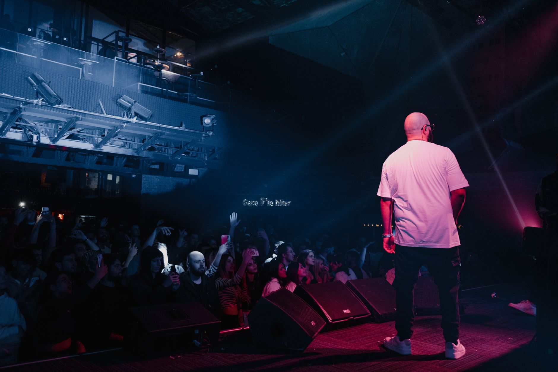 Rapper performing live on stage with vibrant lighting and engaged audience in a concert setting. — Trójmiasto
