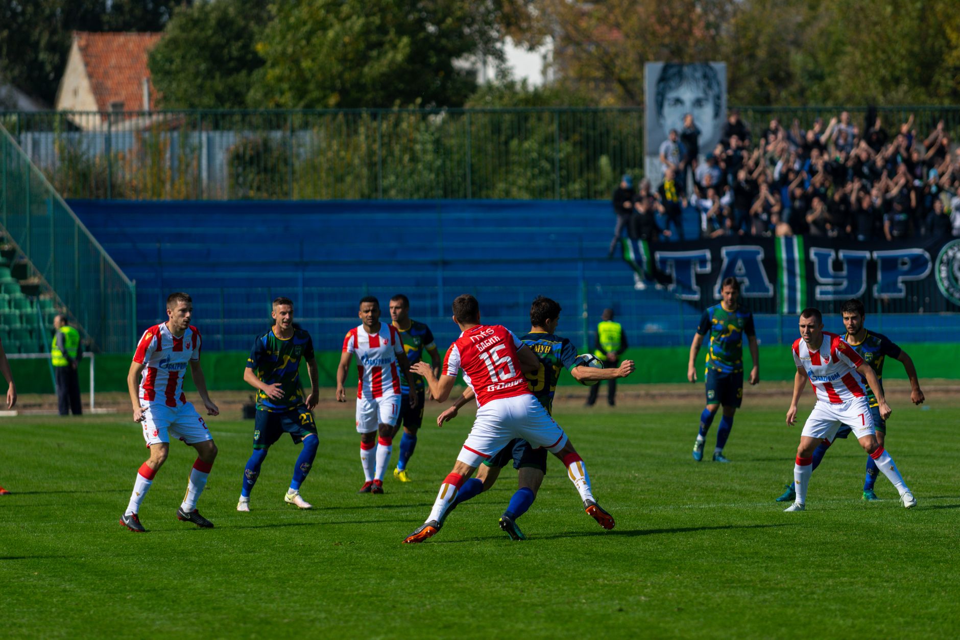 Intense soccer game with teams in action under bright sunlight, surrounded by cheering fans. — Trójmiasto