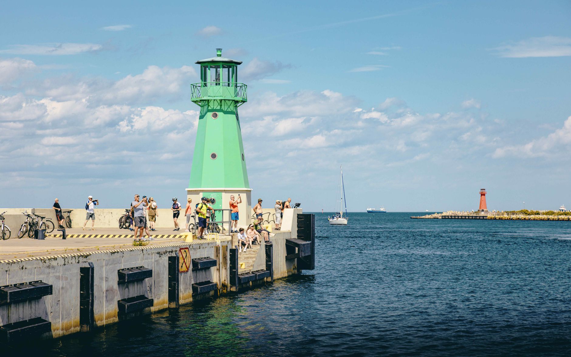 People enjoying a sunny day by the lighthouse pier in Gdańsk, Poland. — Trójmiasto