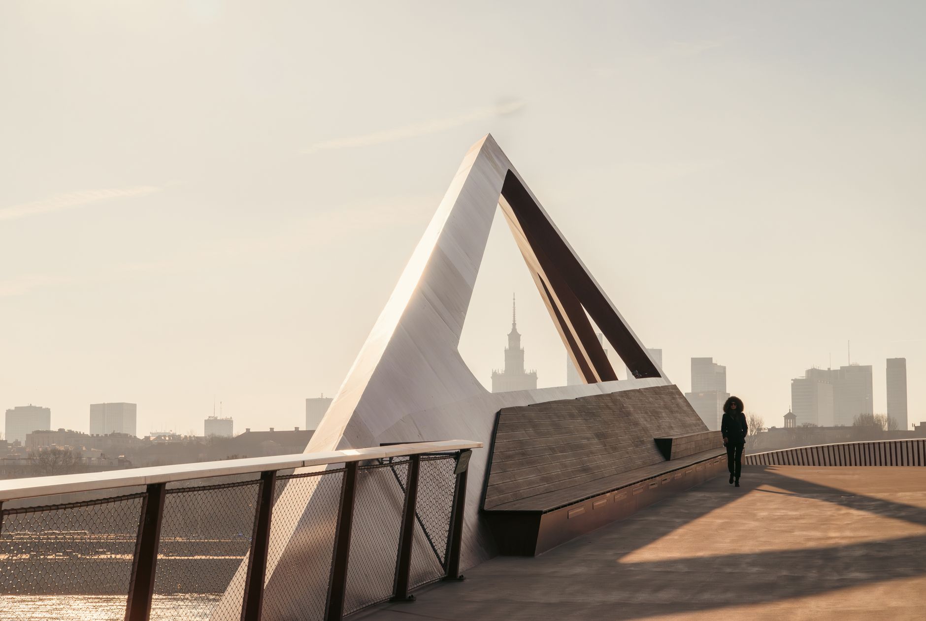 A striking modern structure in Warsaw's cityscape with a person walking nearby. — Trójmiasto