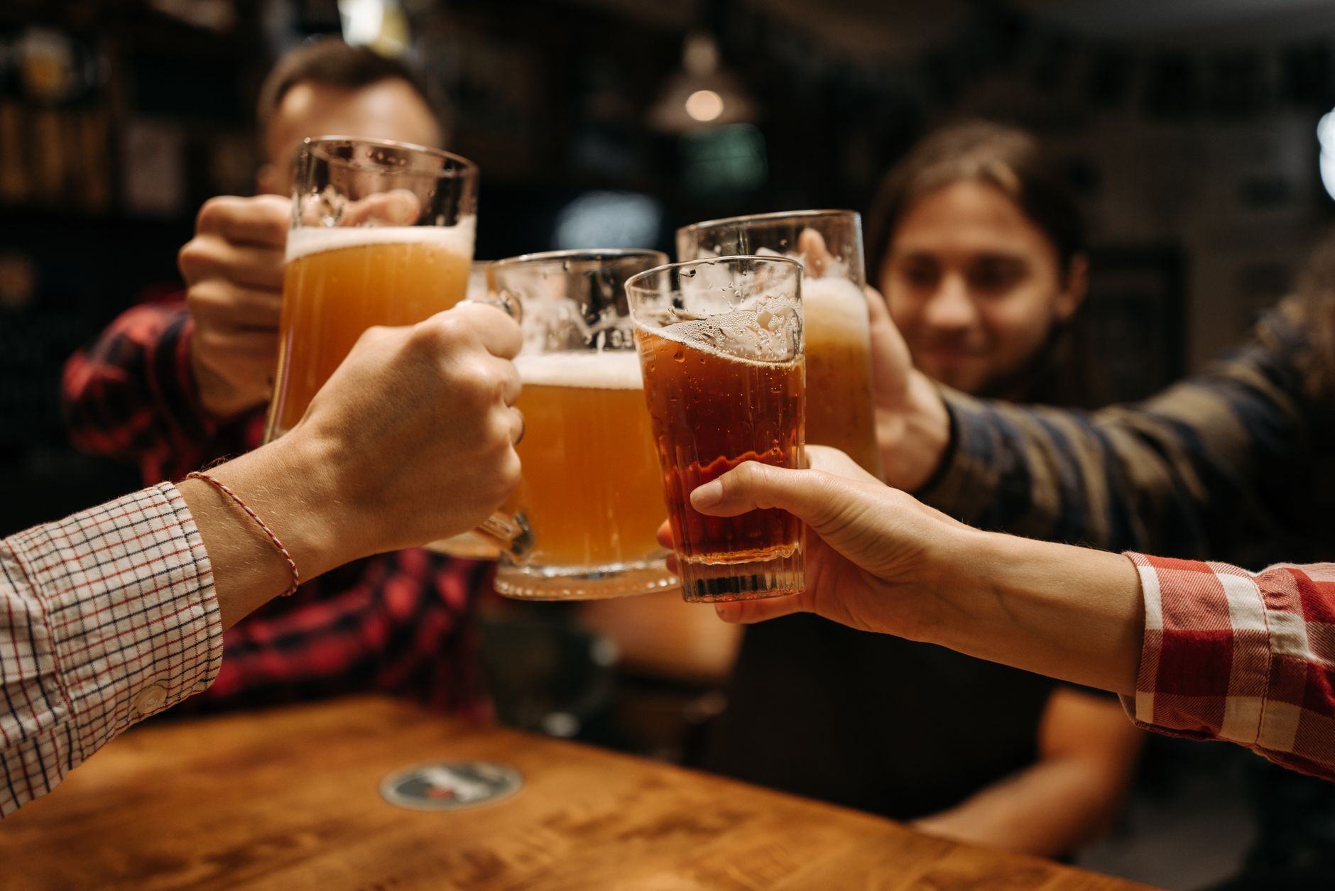 Celebratory toast with beer mugs among friends indoors, capturing fun and friendship. — Trójmiasto