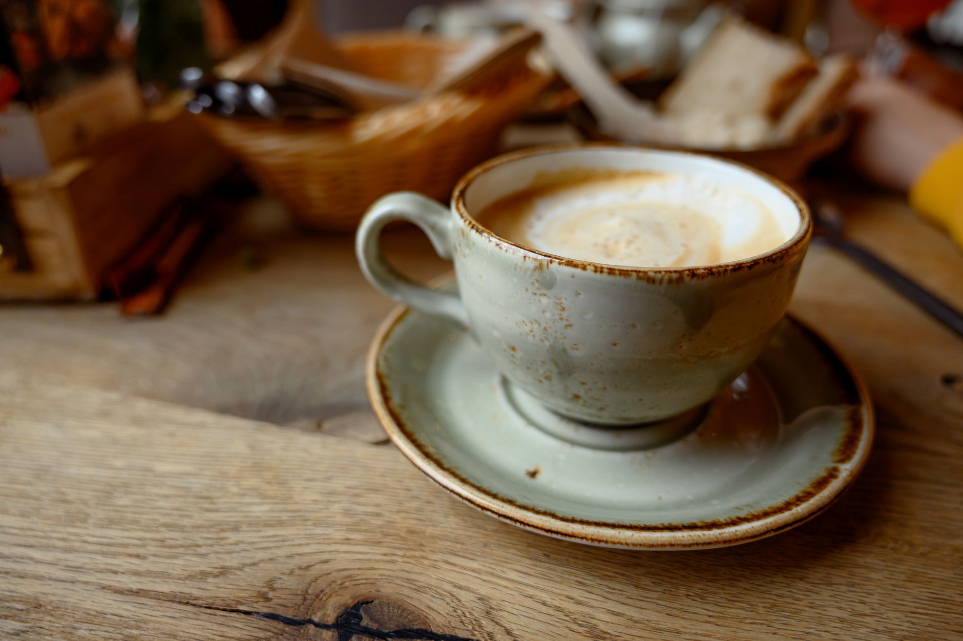 Enjoy a warm cappuccino served in a rustic ceramic cup on a wooden table, perfect for cozy moments. — Trójmiasto