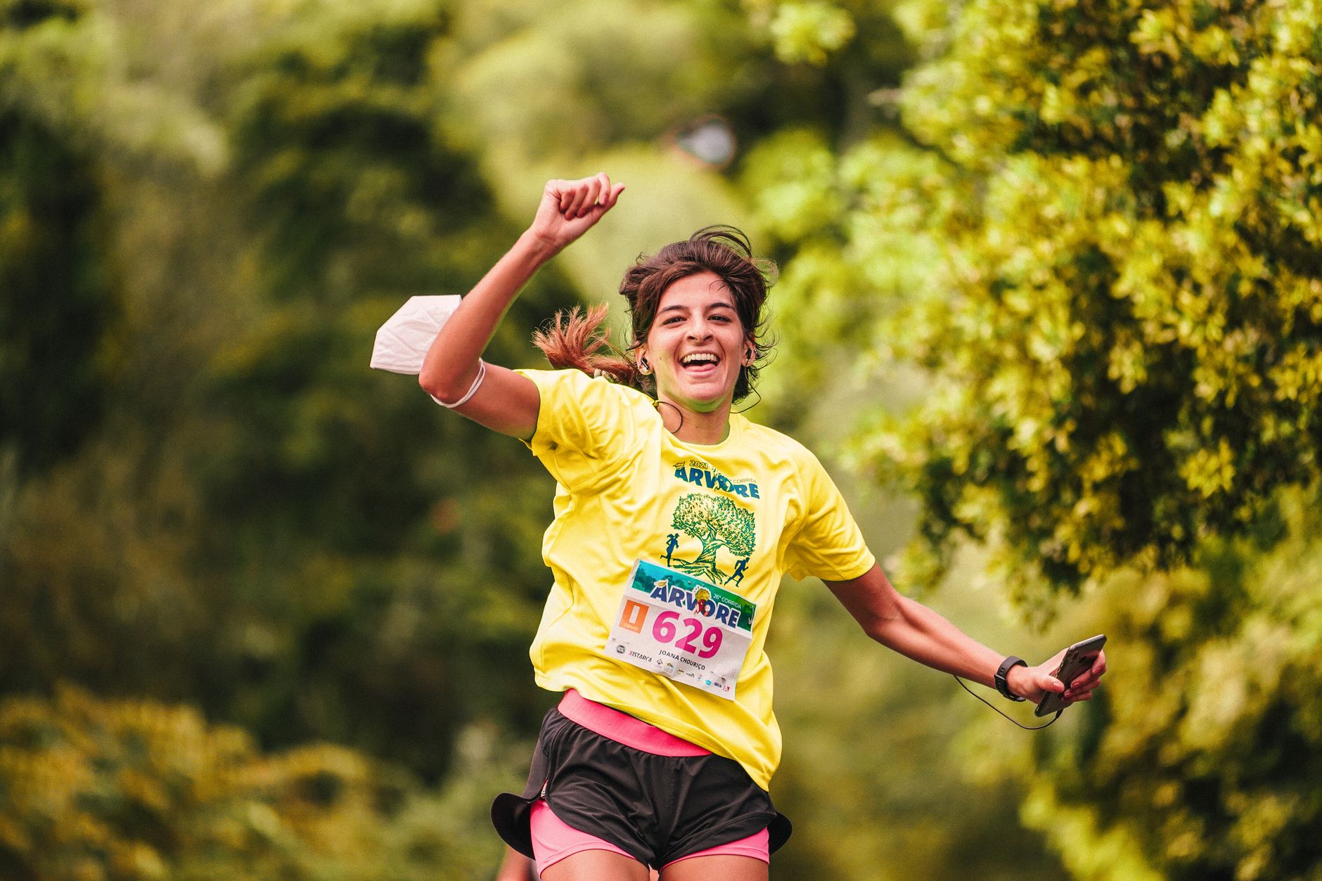 Joyful female runner in yellow participates in an outdoor race amidst lush greenery, embodying athletic enthusiasm. — Trójmiasto