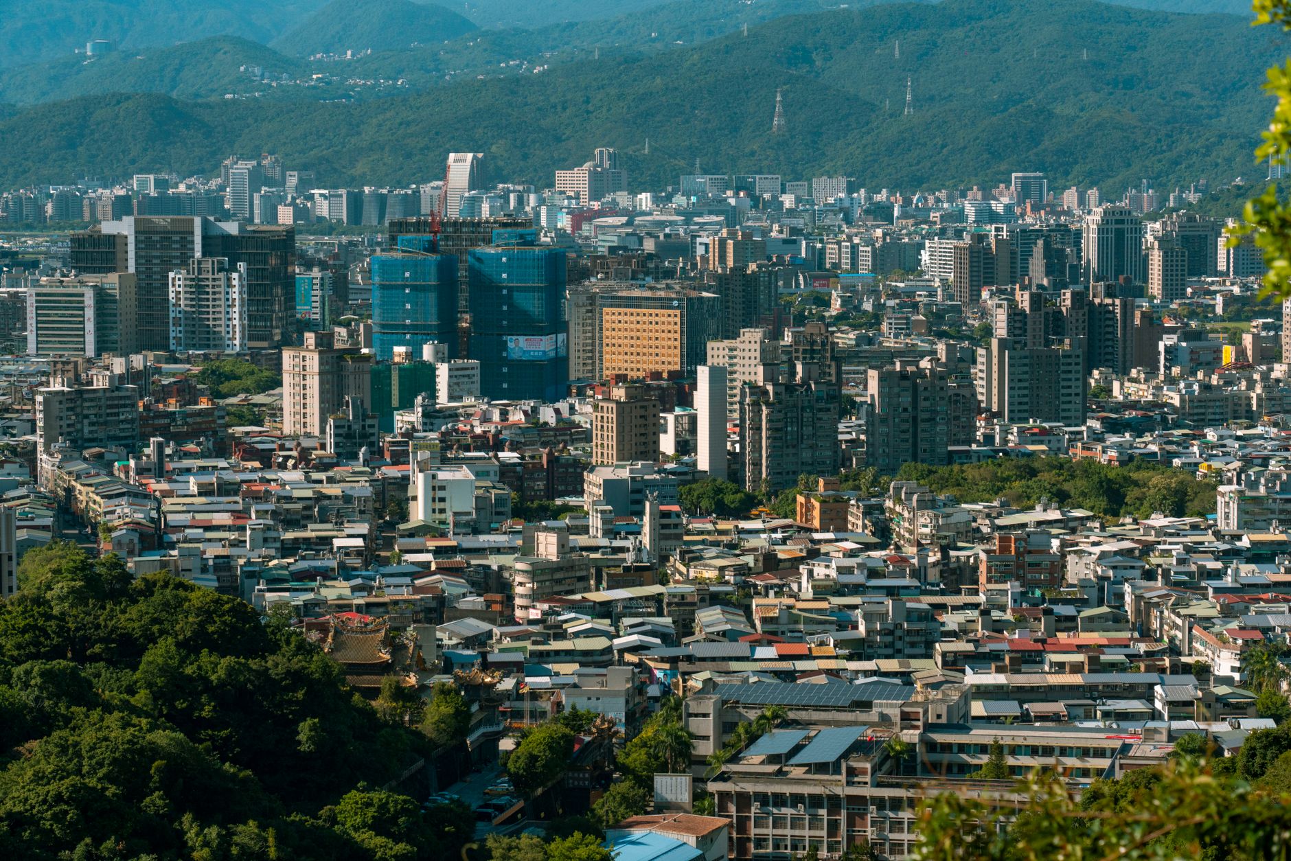 A vibrant aerial shot of Taipei's bustling cityscape surrounded by lush green mountains. — Trójmiasto