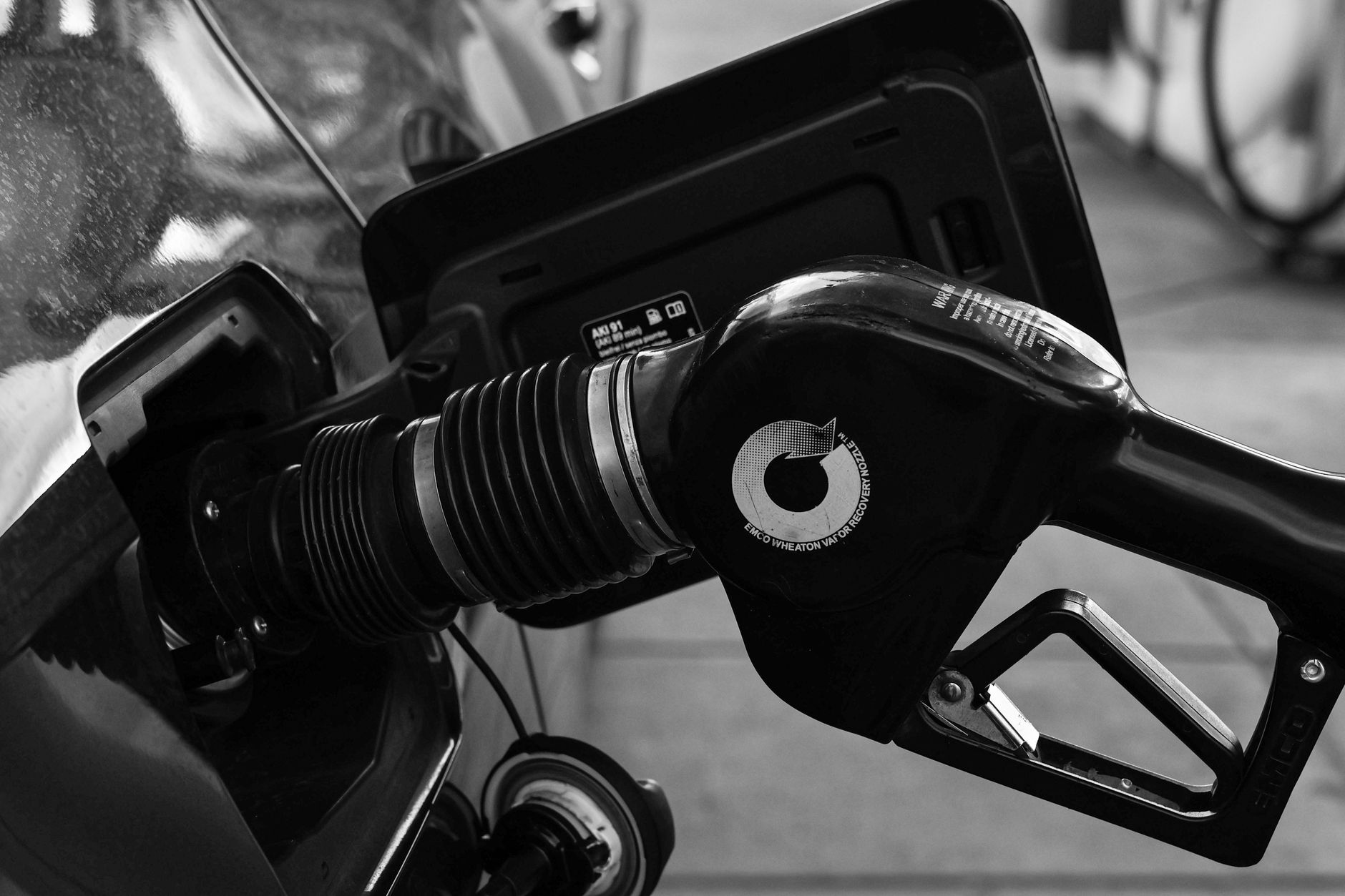 Detailed close-up of a refueling nozzle in monochrome at a gas station, highlighting the petrol filling process. — Trójmiasto