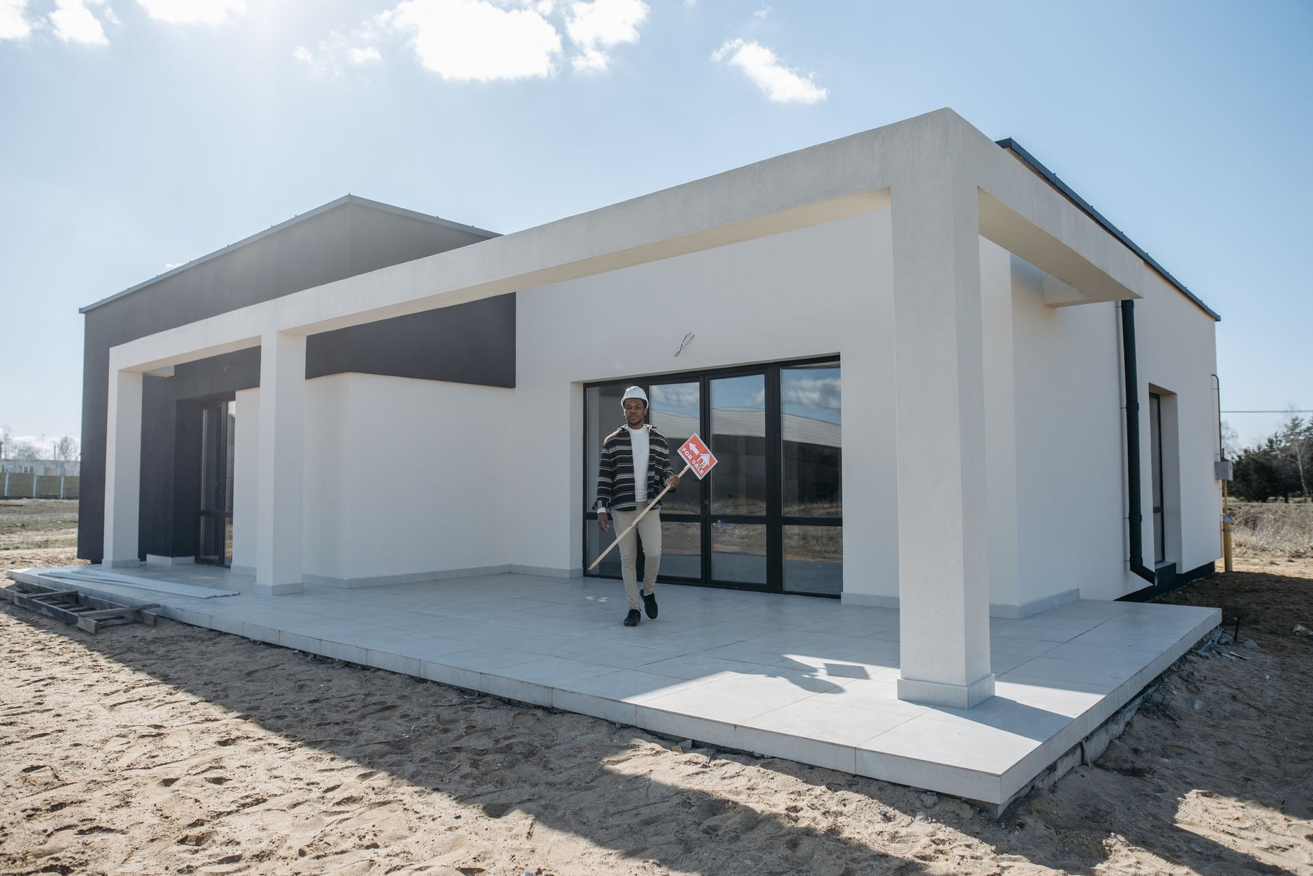 Real estate agent holding a for sale sign in front of a new modern house. — Trójmiasto