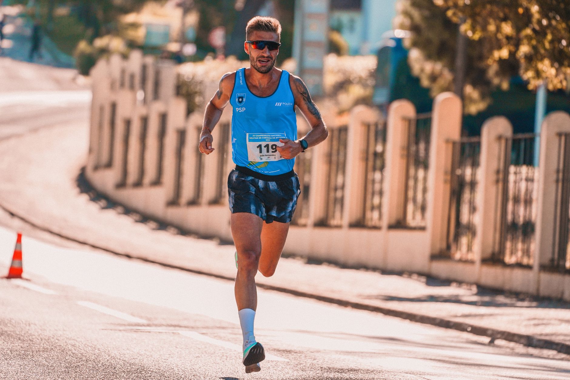 Male athlete running in an urban marathon under sunny conditions. — Trójmiasto