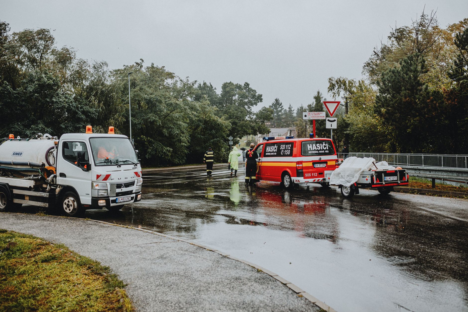 Emergency services attending a scene on a rainy road with rescue vehicles and personnel. — Trójmiasto
