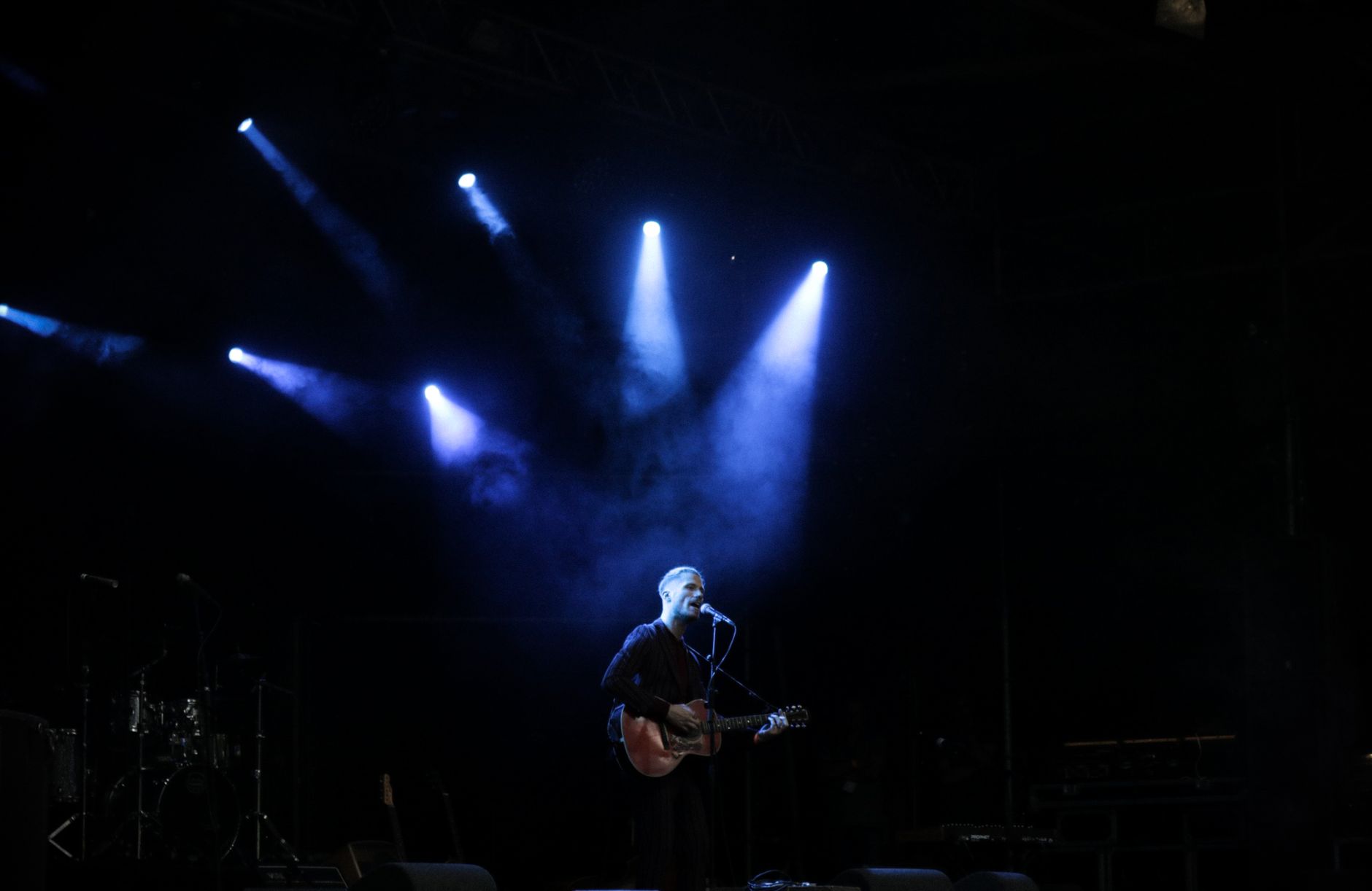 Solo musician performs on stage with guitar under dramatic blue lighting during a live concert. — Trójmiasto