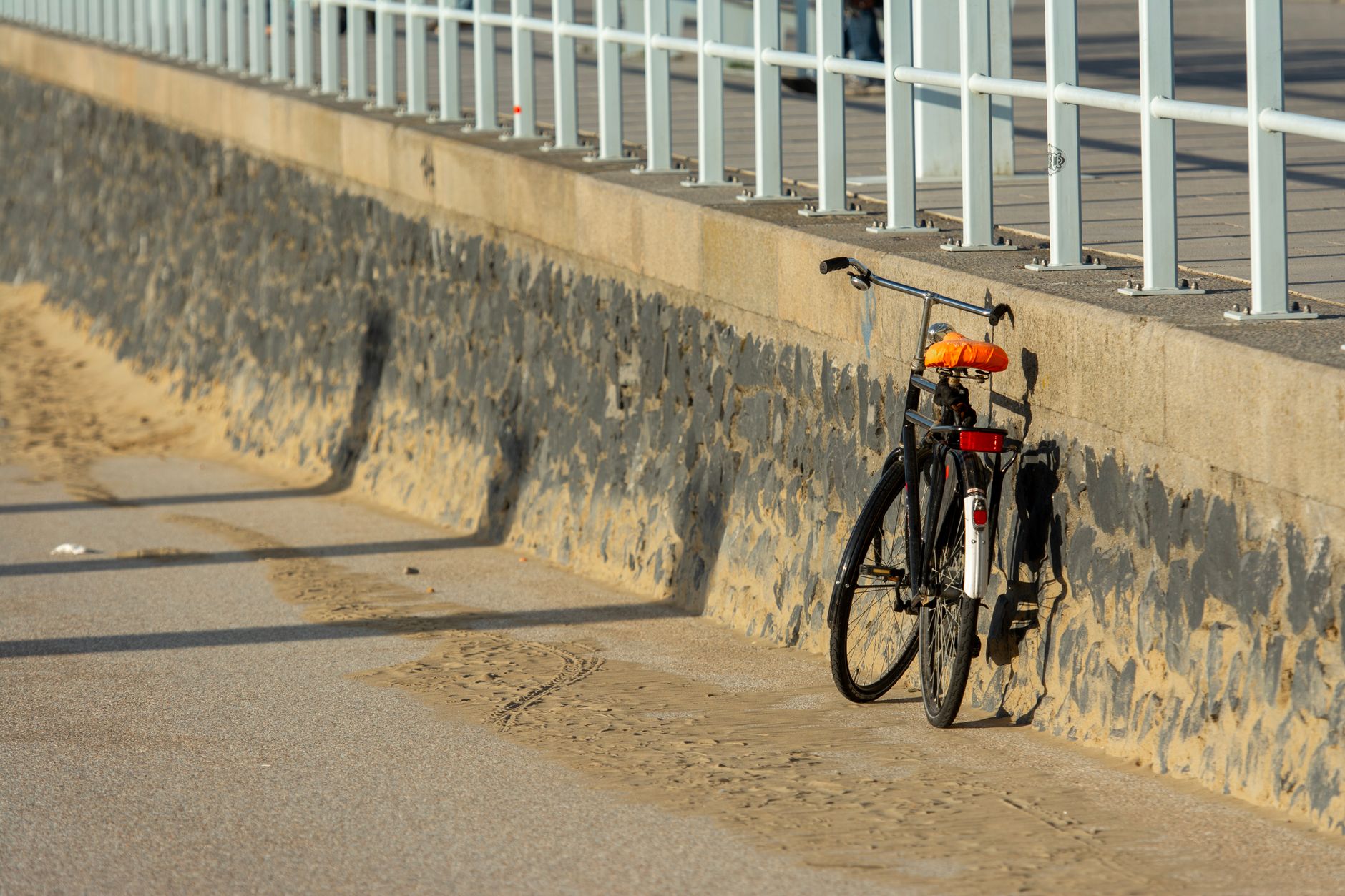 A retro bicycle resting against a seaside promenade wall on a sunny day. — Trójmiasto