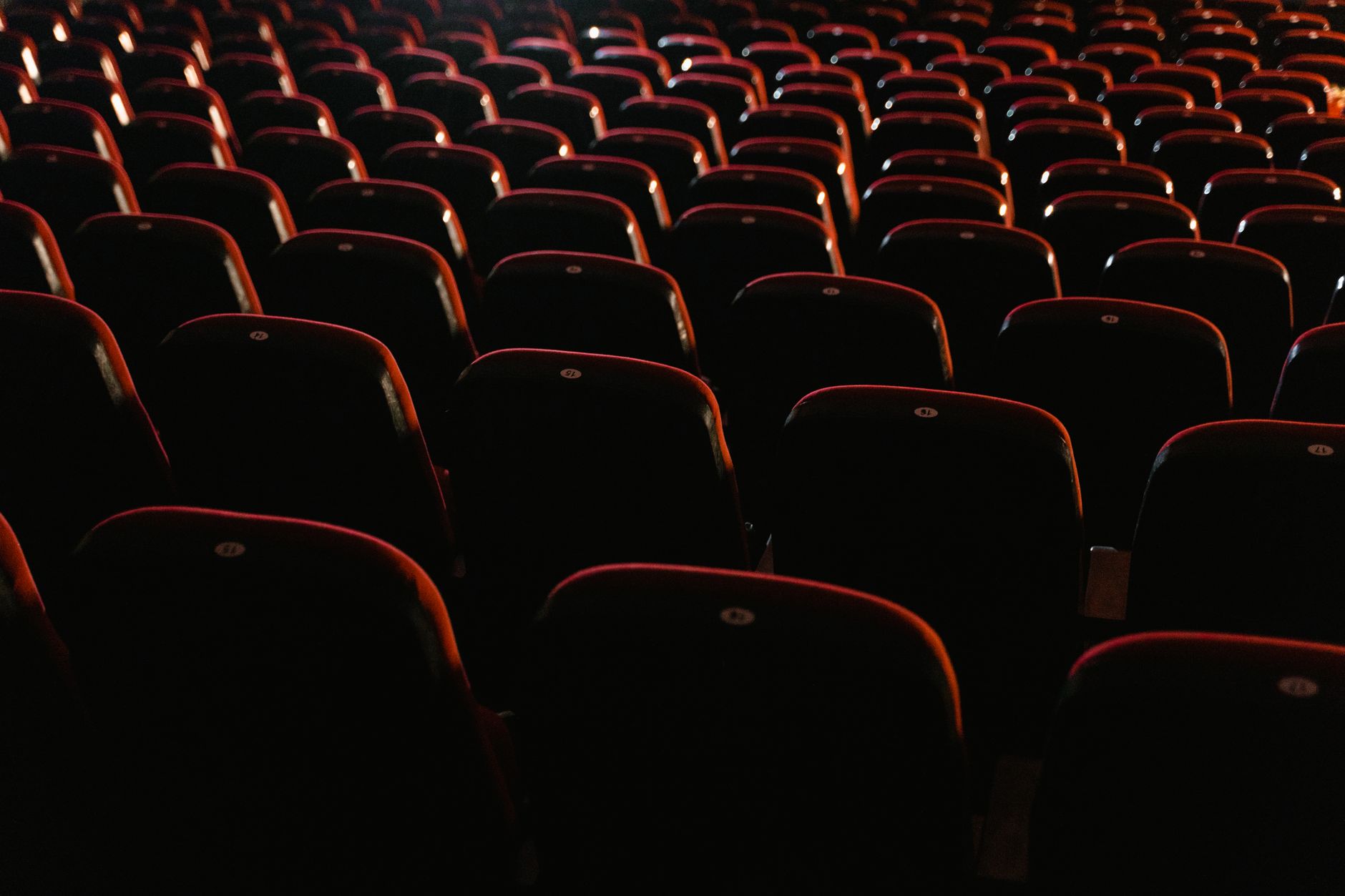 Rows of empty red seats in a dimly lit movie theater, showcasing a cinema environment. — Trójmiasto