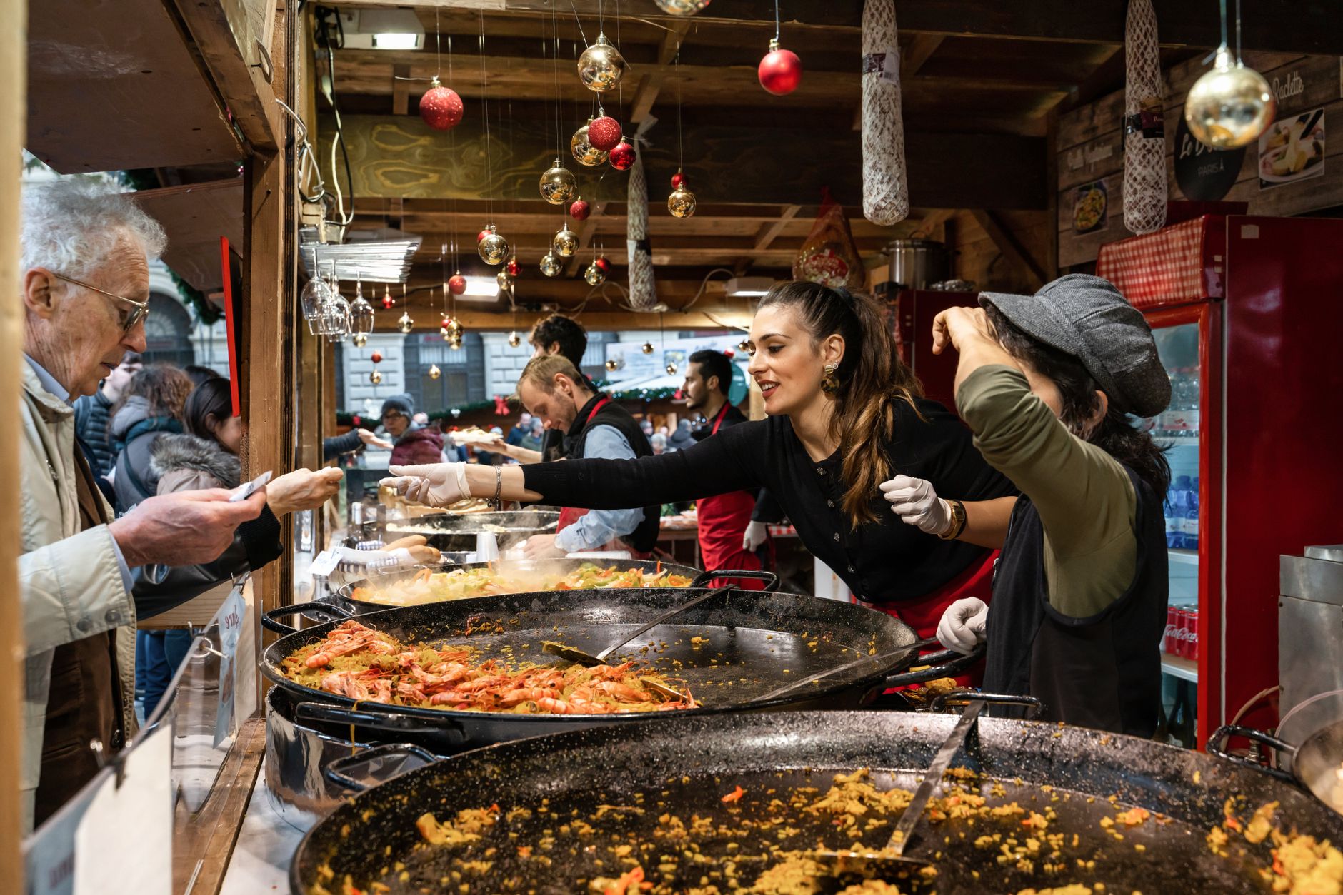 Vibrant market scene with people enjoying paella during the holiday season. — Trójmiasto